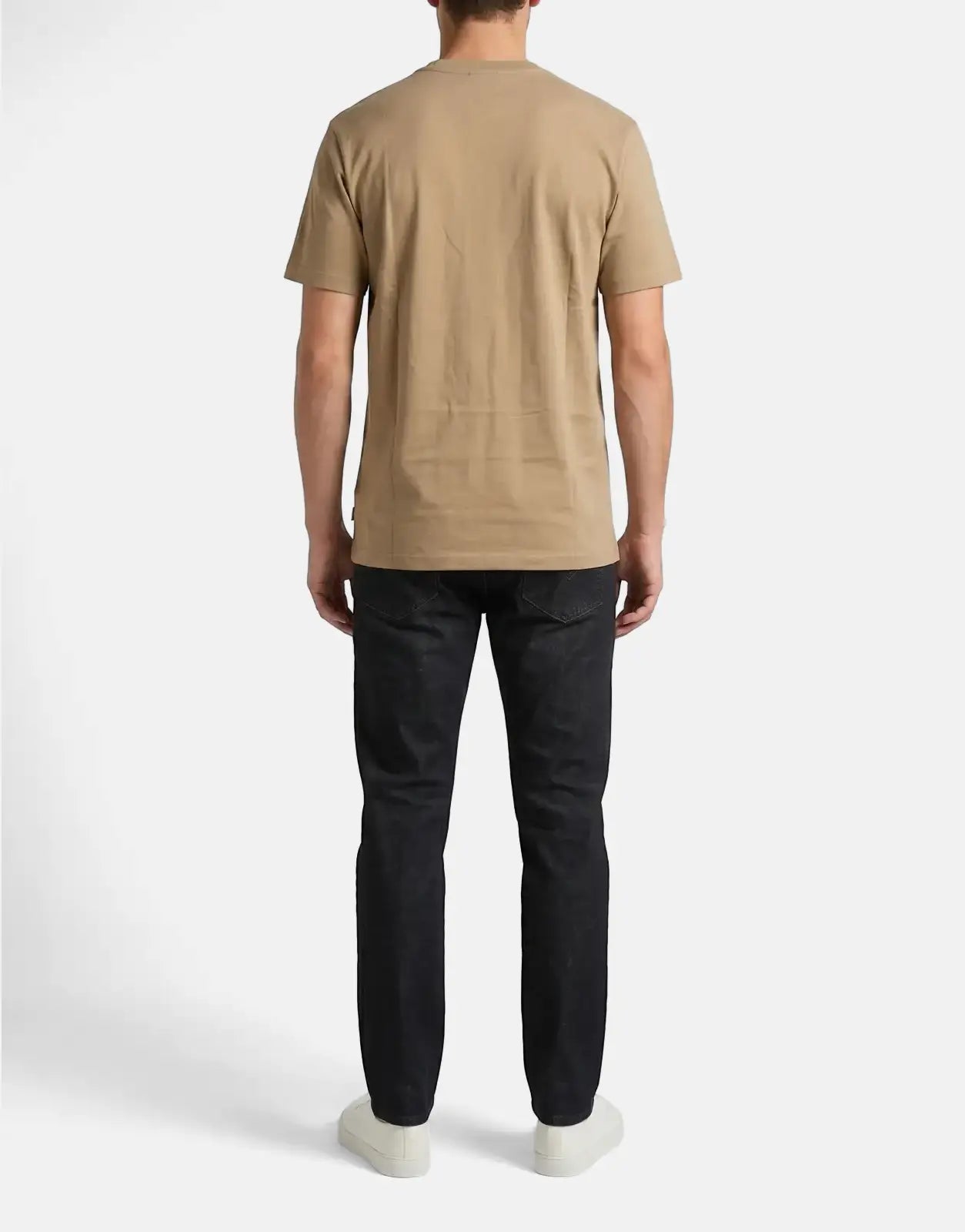 Rear view of a male model wearing a tan Ben Sherman Target Cornstalk T-Shirt, dark wash jeans, and white sneakers.
