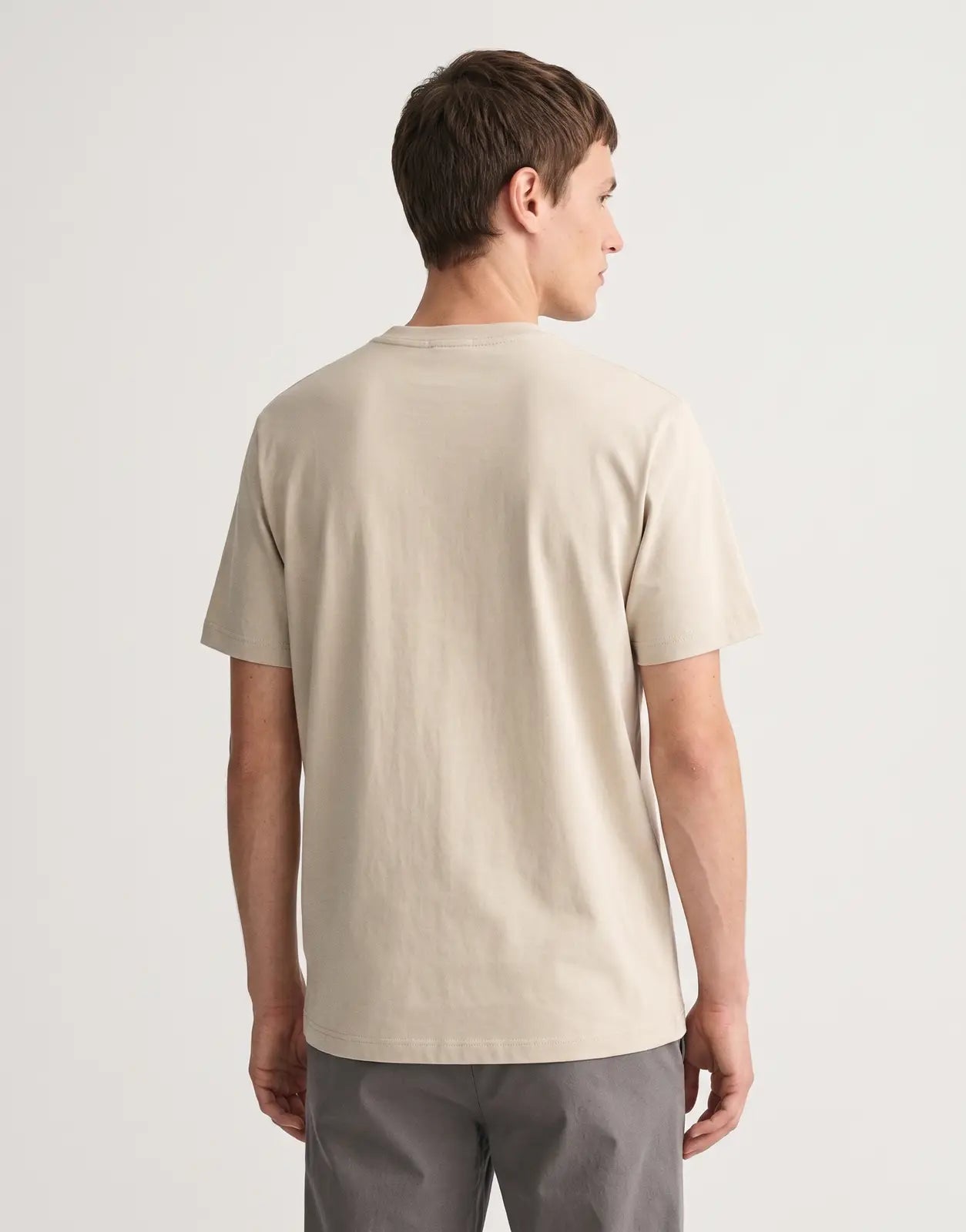 Calvin Klein 30s Wholesale Graphic Beige T-Shirt, featuring a plain back, short sleeves, and a crew neck, displayed on a