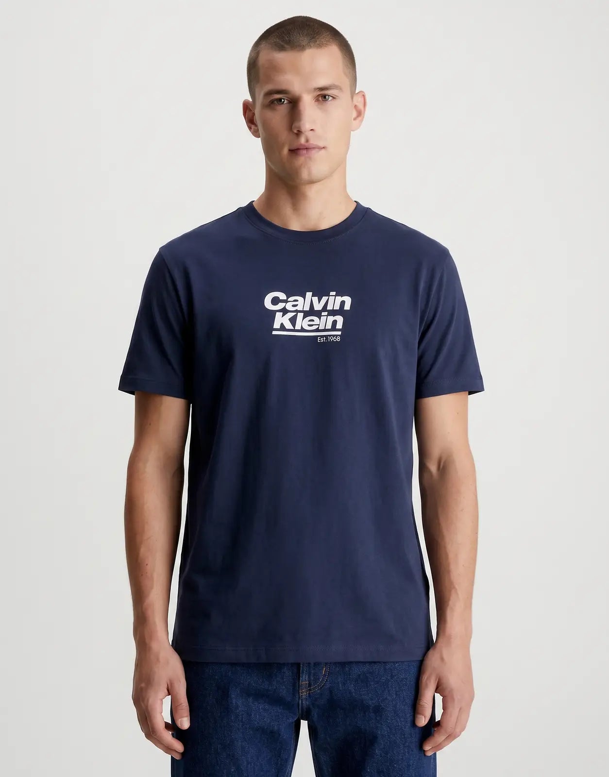 A navy blue Calvin Klein 30s Wholesale Jeans Graphic T-Shirt for men, featuring a white 'Calvin Klein Est. 1968' logo on the