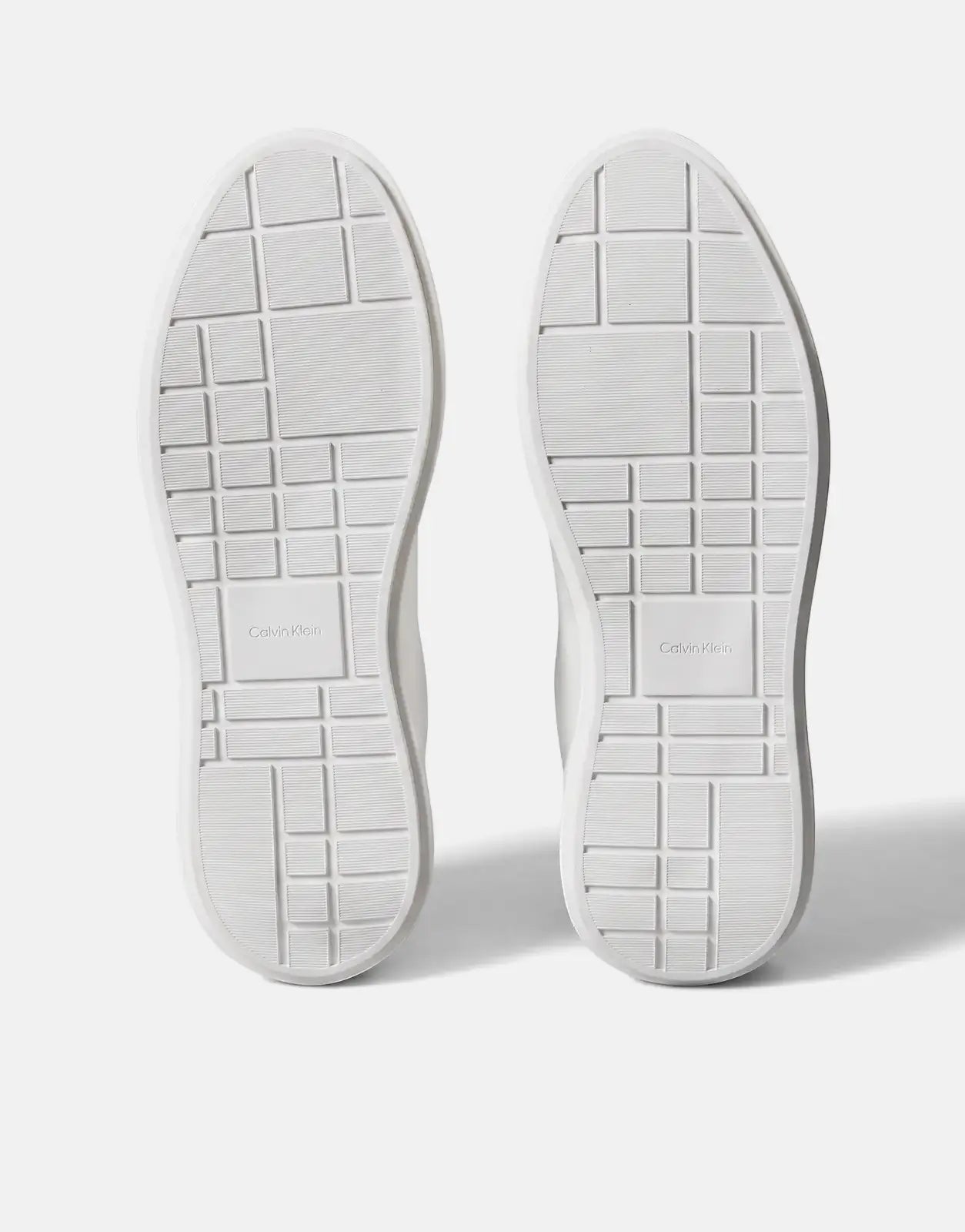 Pair of Calvin Klein Chunky Cupsole sneakers in white, showing the textured outsoles with logo details.