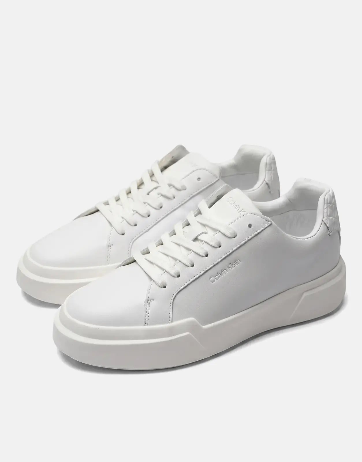 Two white Calvin Klein Chunky Cupsole sneakers with embossed logo detailing, viewed from a slight angle on a neutral