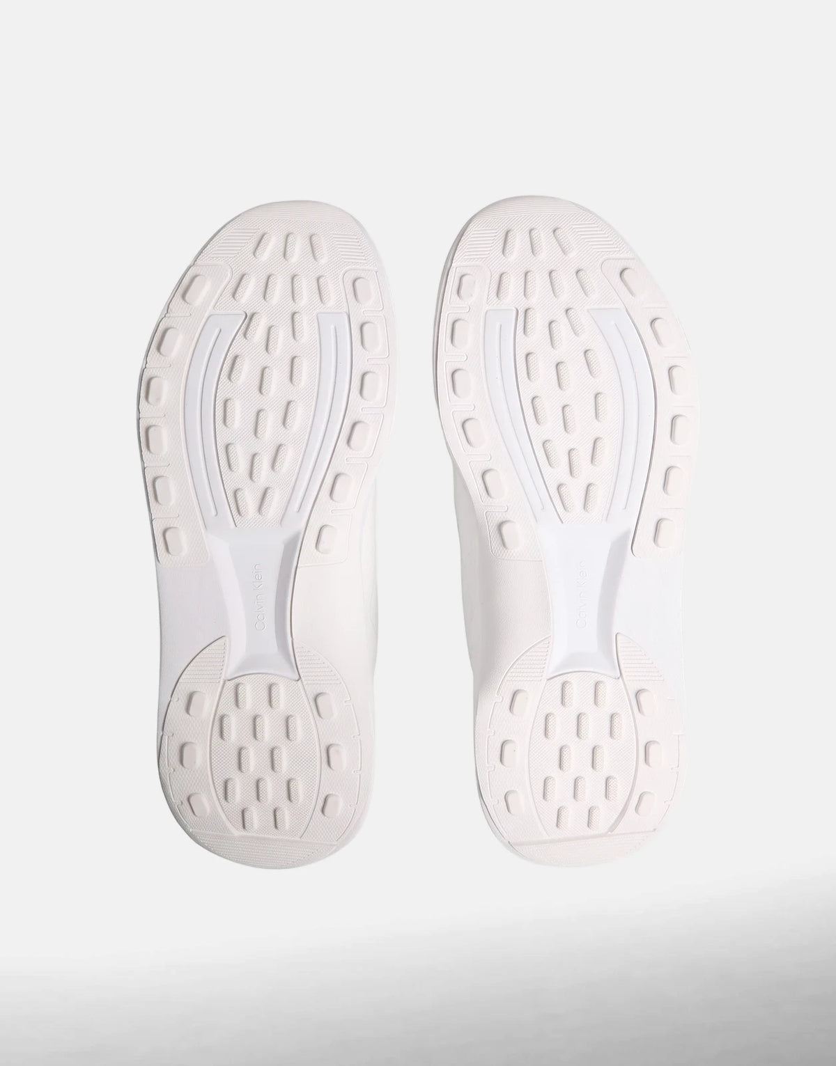 White Calvin Klein Chunky Run Lacesock Stripe sneakers, bottom view showing the patterned white rubber soles floating