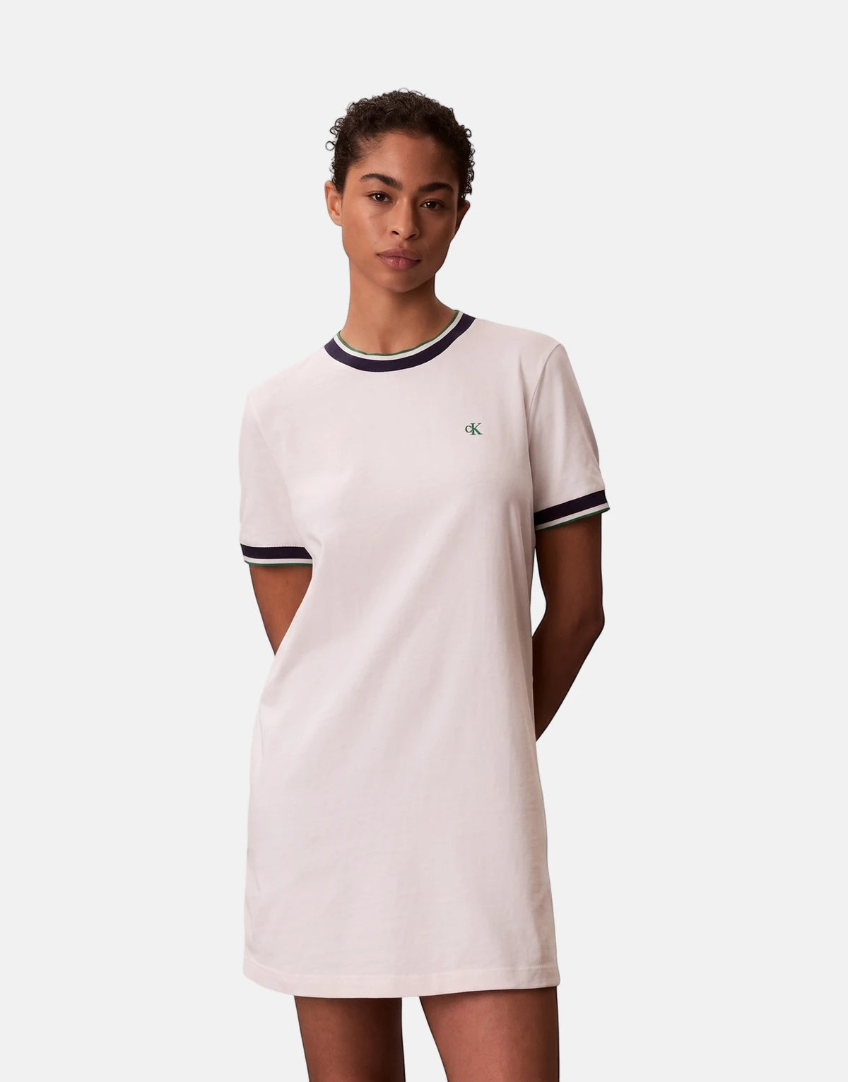 Female model wearing white Calvin Klein CTN Monogram Stripe Trim mini dress with navy and green details and CK logo.
