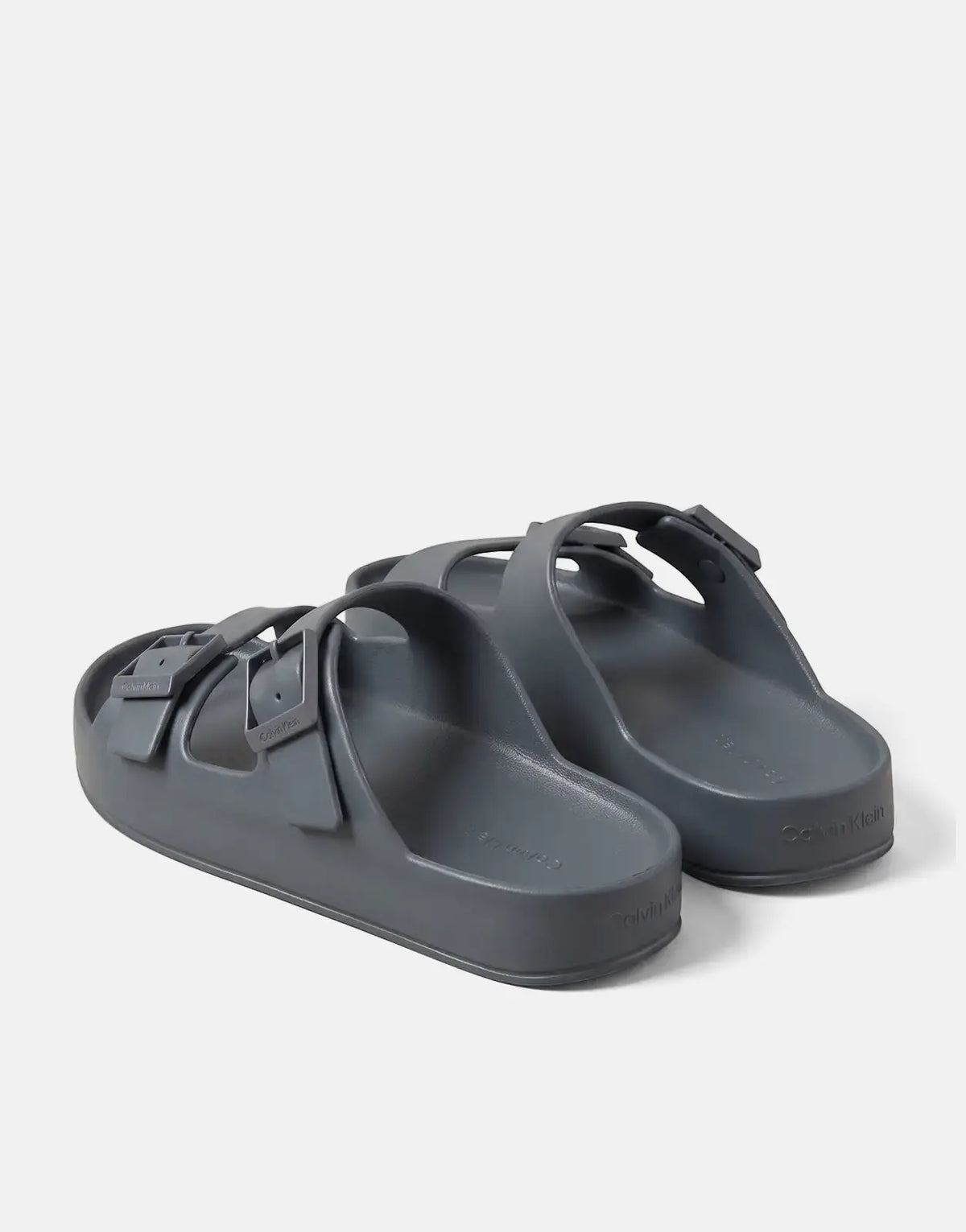 A pair of blue-grey Calvin Klein Ergon Eva double bar sandals, made of molded EVA, shown from a rear-quarter view.