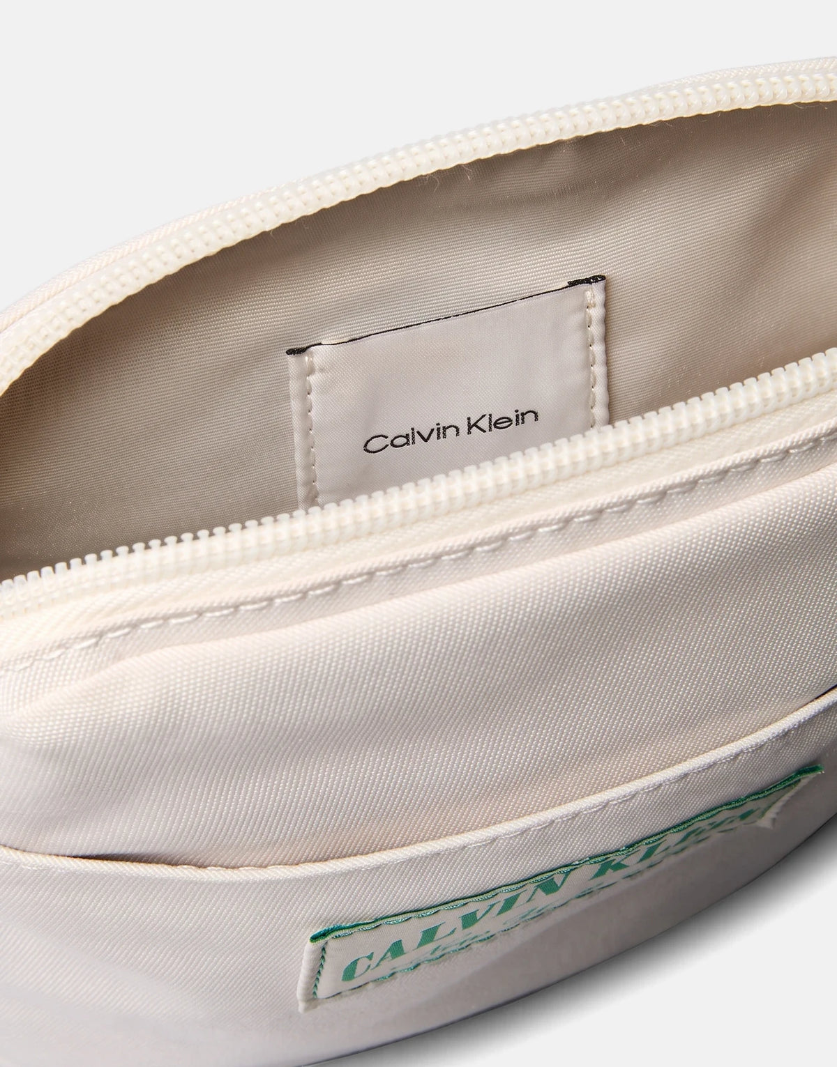Close-up of an open off-white Calvin Klein Graphic Capsule Reporter bag, highlighting its main compartment, internal brand
