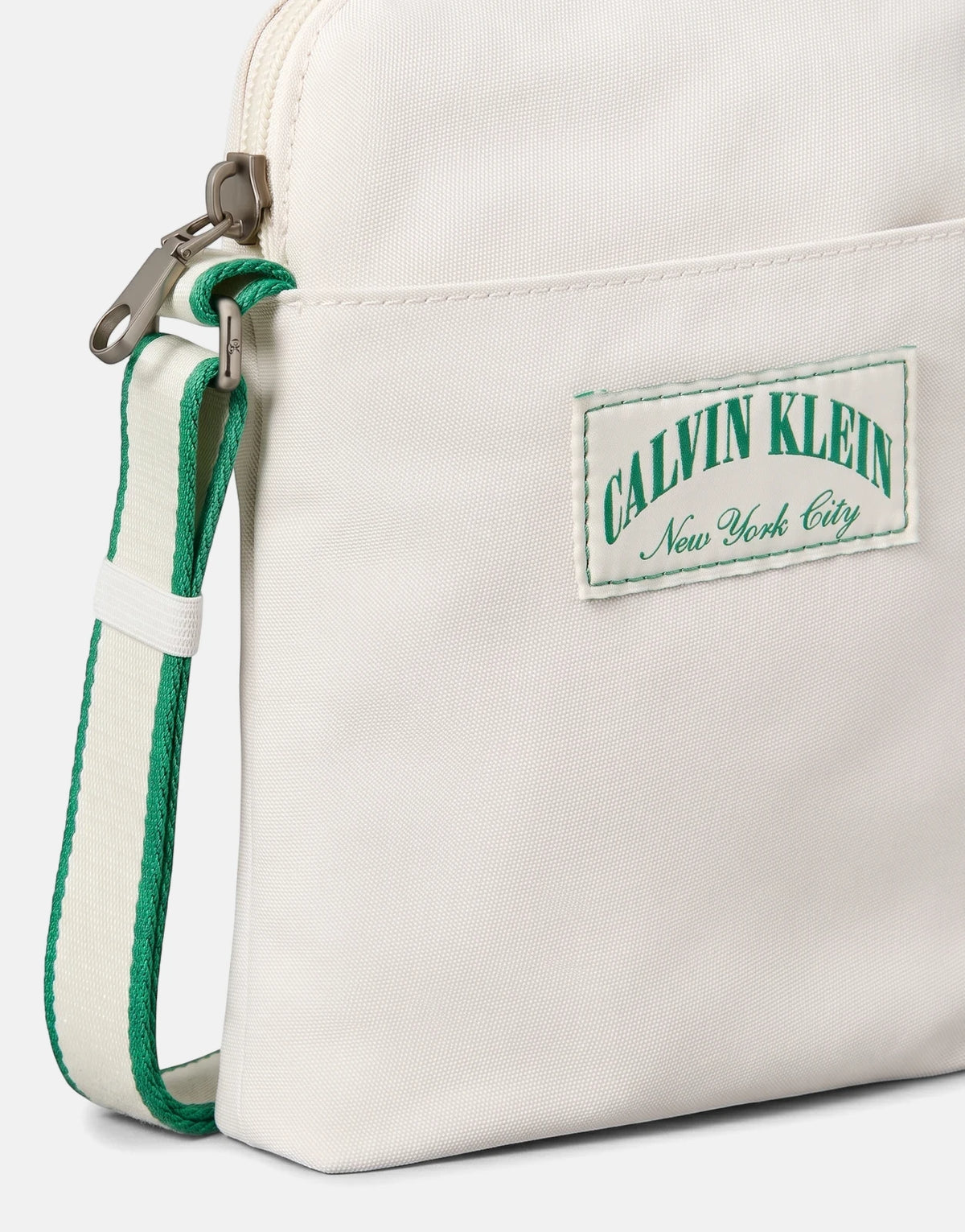 Close-up of a Calvin Klein Graphic Capsule Reporter Off White Bag, featuring a green and white striped strap and a 'CALVIN