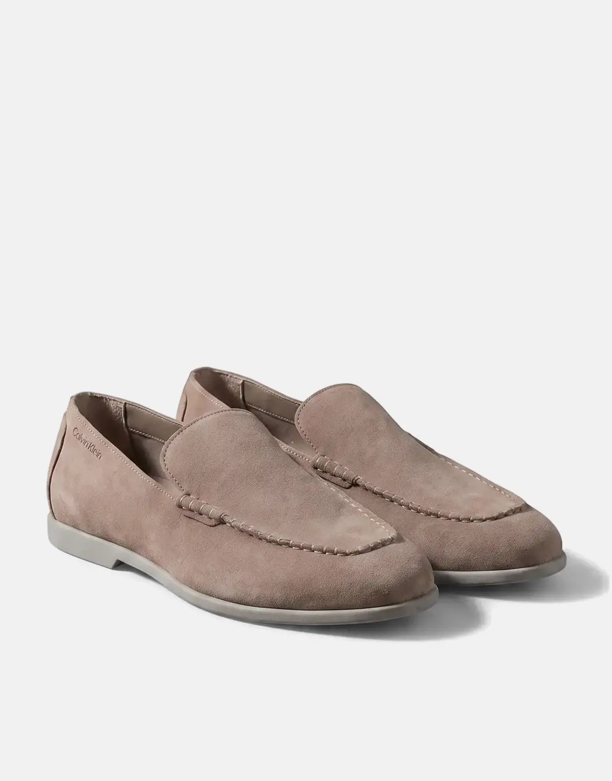 Pair of Calvin Klein Low Prof taupe suede moc toe loafers with white stitching details, displayed on a neutral background.