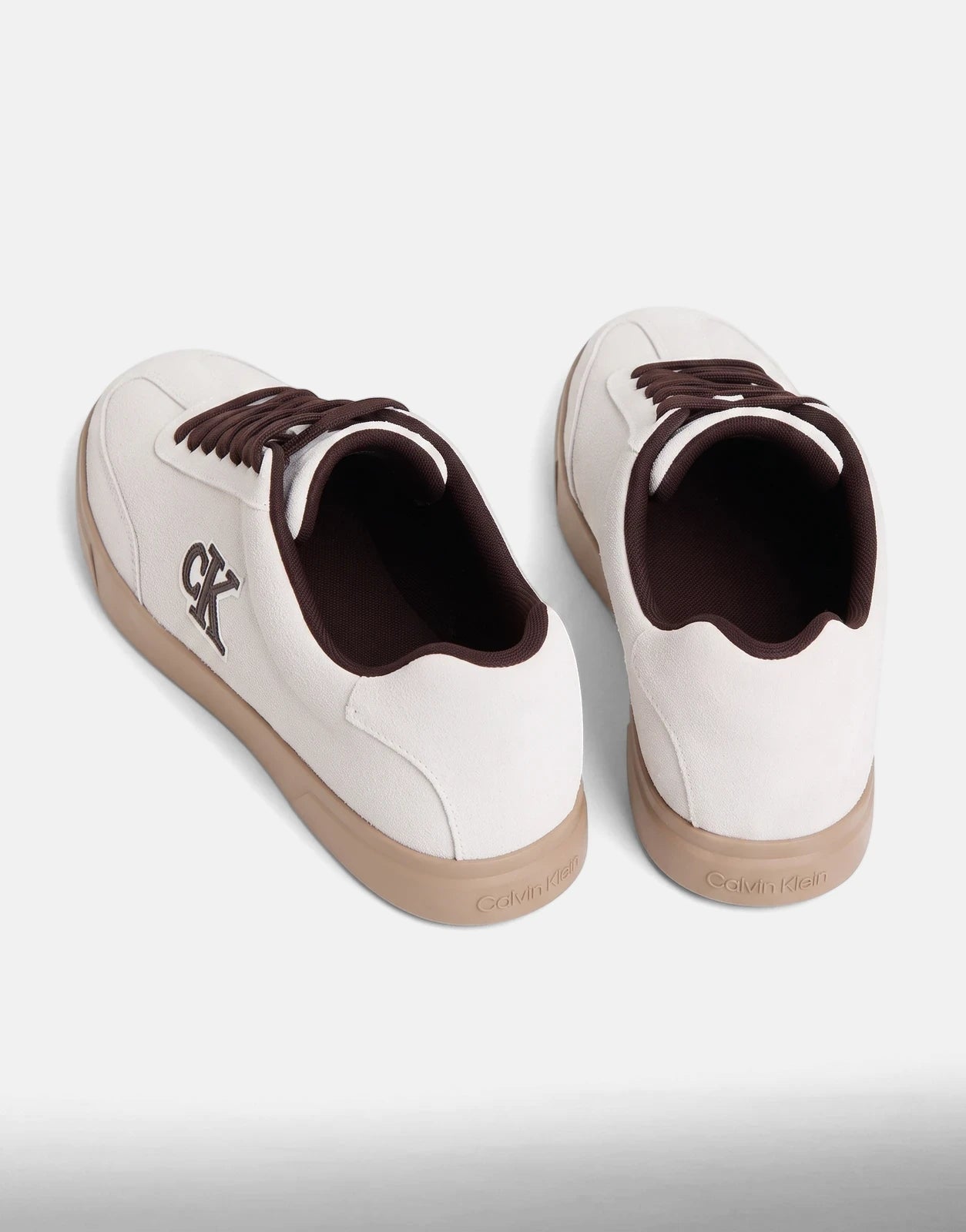 Two Calvin Klein Low Prof White Multi Cupsole Sneakers with brown laces and tan soles, shown from an elevated perspective.