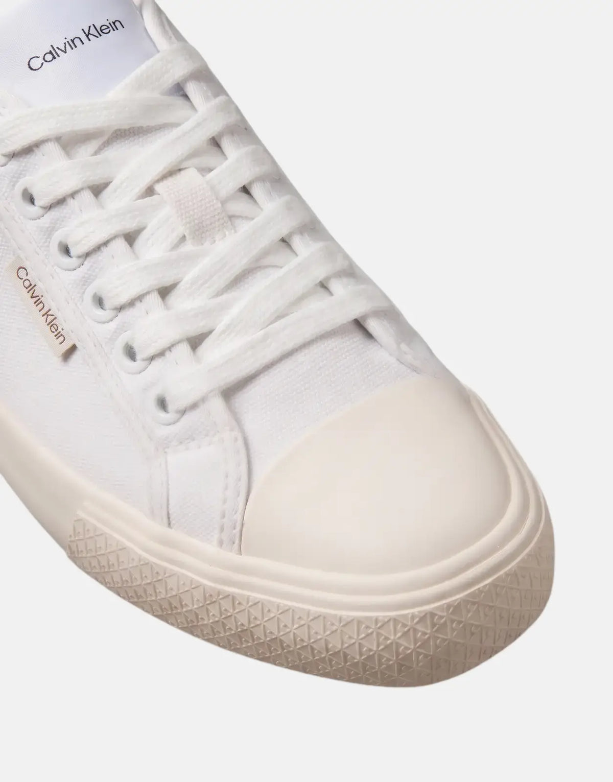Close-up of a white Calvin Klein Vulc Low Laceup canvas sneaker with cream toe cap and sole details.
