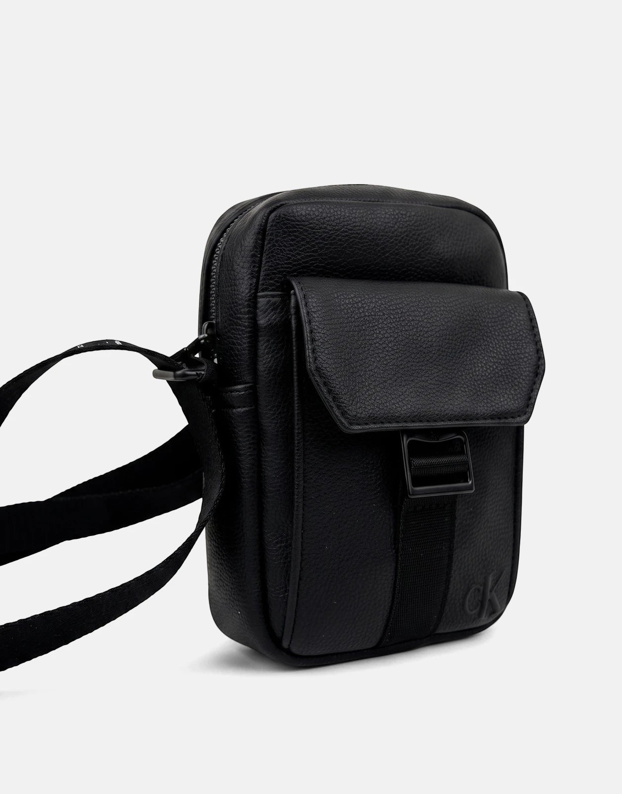 Black Calvin Klein webbing strap slim reporter bag, made of textured faux leather, featuring a front flap pocket and a top