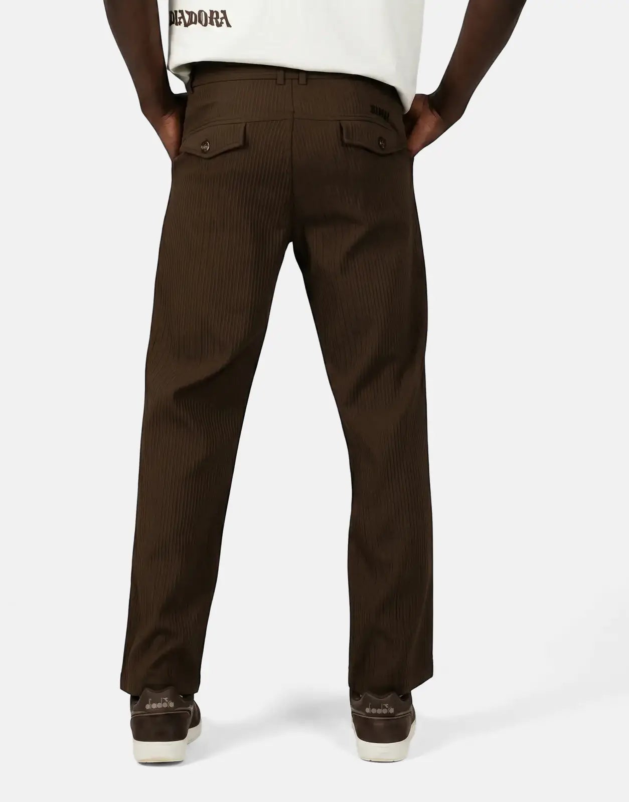 Diadora Asher men's brown ribbed pants, shown from the back, worn by a model standing with hands in pockets.