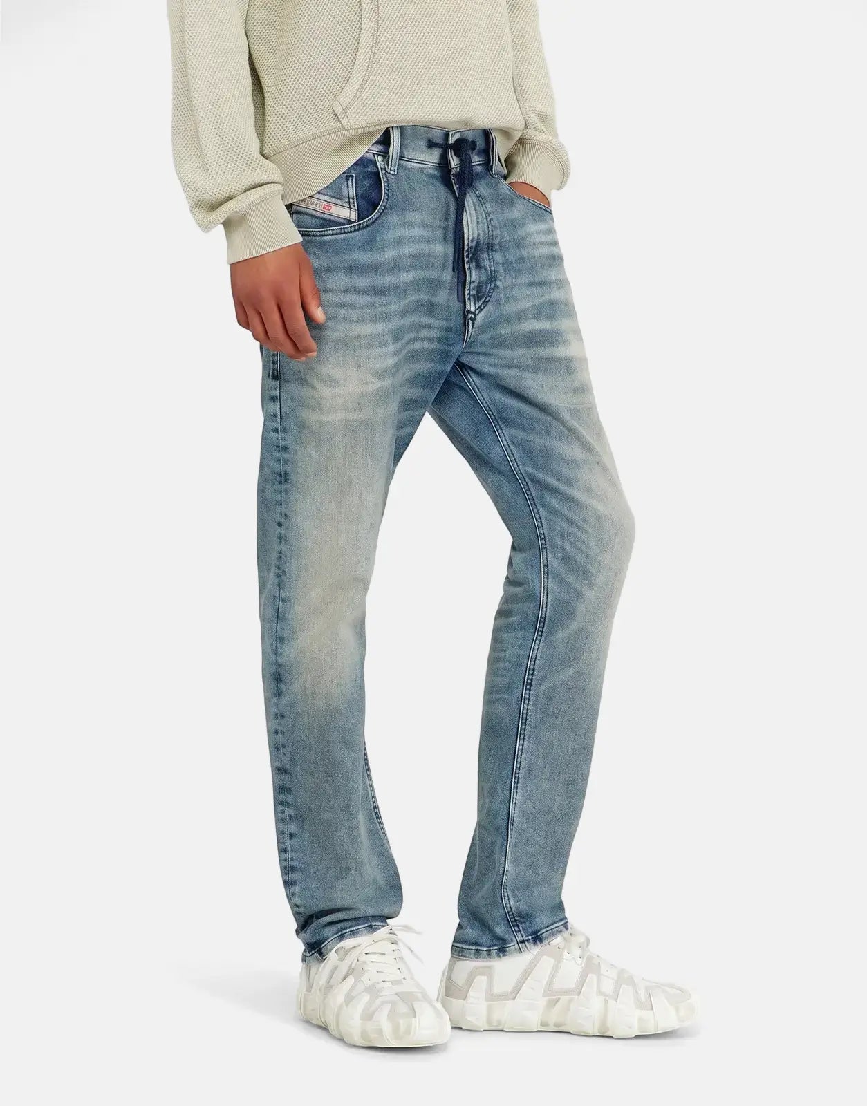 Men's light blue Diesel 2032 D-Krooley B distressed denim jogger jeans, styled with a light cream hoodie and chunky white