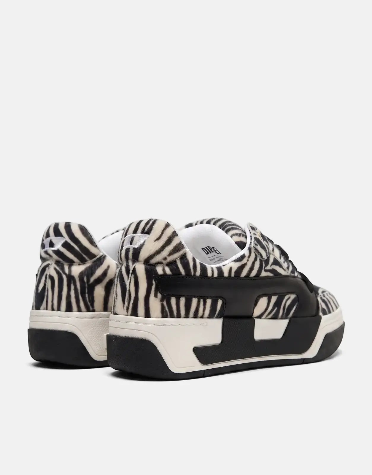 Pair of Diesel D-Ollie Low sneakers in black and white zebra print, featuring black and white soles, seen from a rear-side
