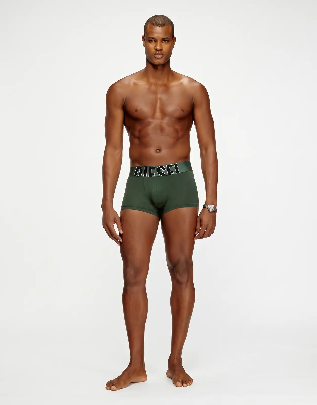 Front view of a male model wearing green Diesel Damien D Pop boxer shorts with a black and grey logo waistband.