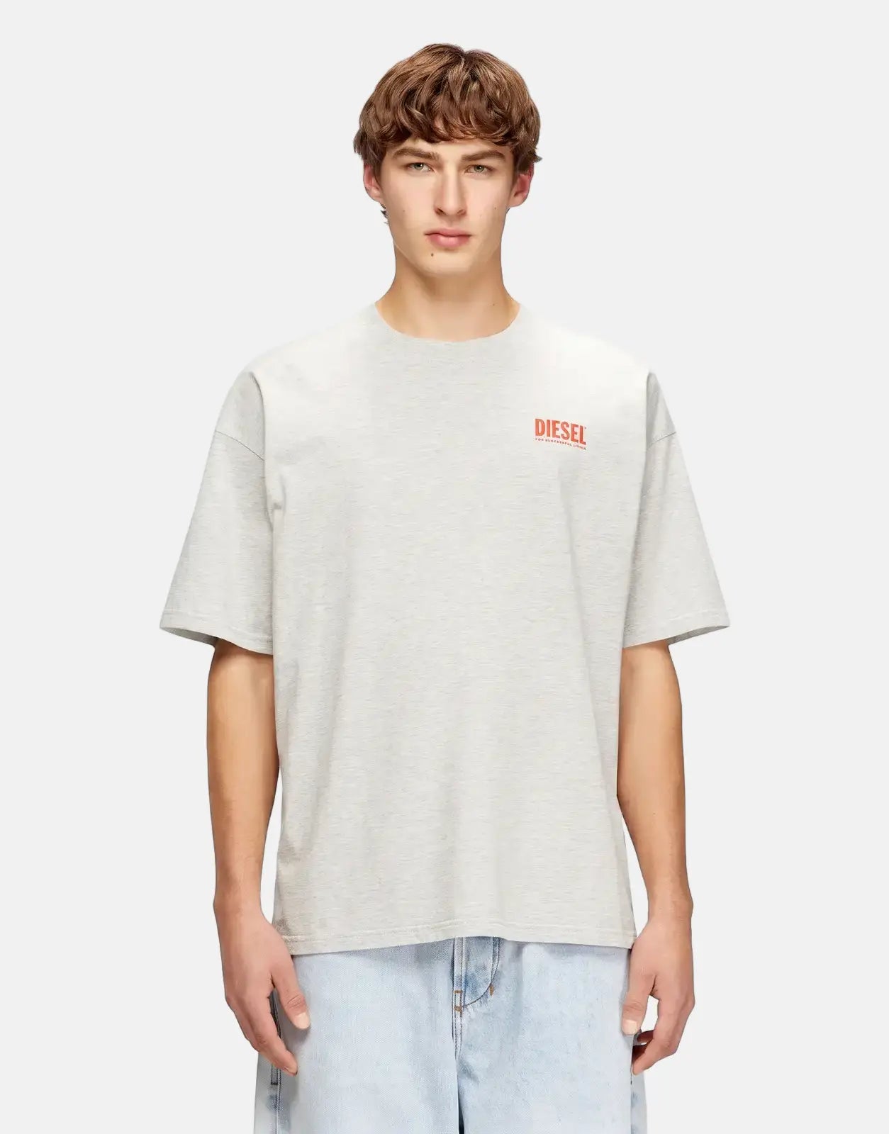 Male model wearing a light grey Diesel T-Boxt Bisk Relaxed T-Shirt with a red logo, paired with light wash jeans.