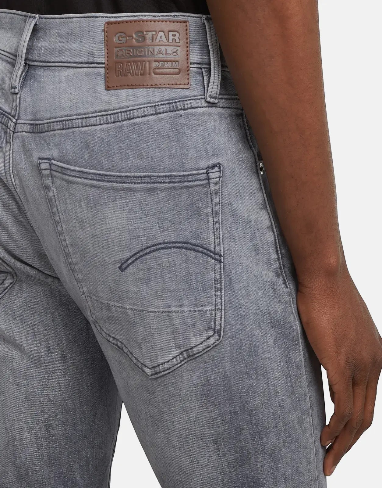 A close-up view of the back of G-Star RAW 3301 Sun Faded Glacier Grey denim jeans, showcasing the leather brand patch and