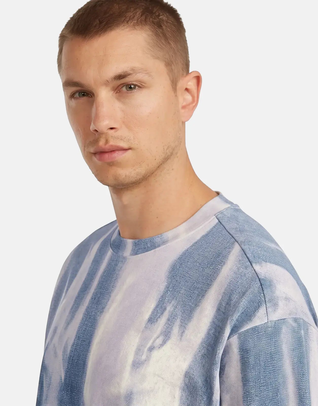 Male model wearing a G-Star RAW All Over Loose Denim Flame T-Shirt, featuring a unique blue and white tie-dye pattern and