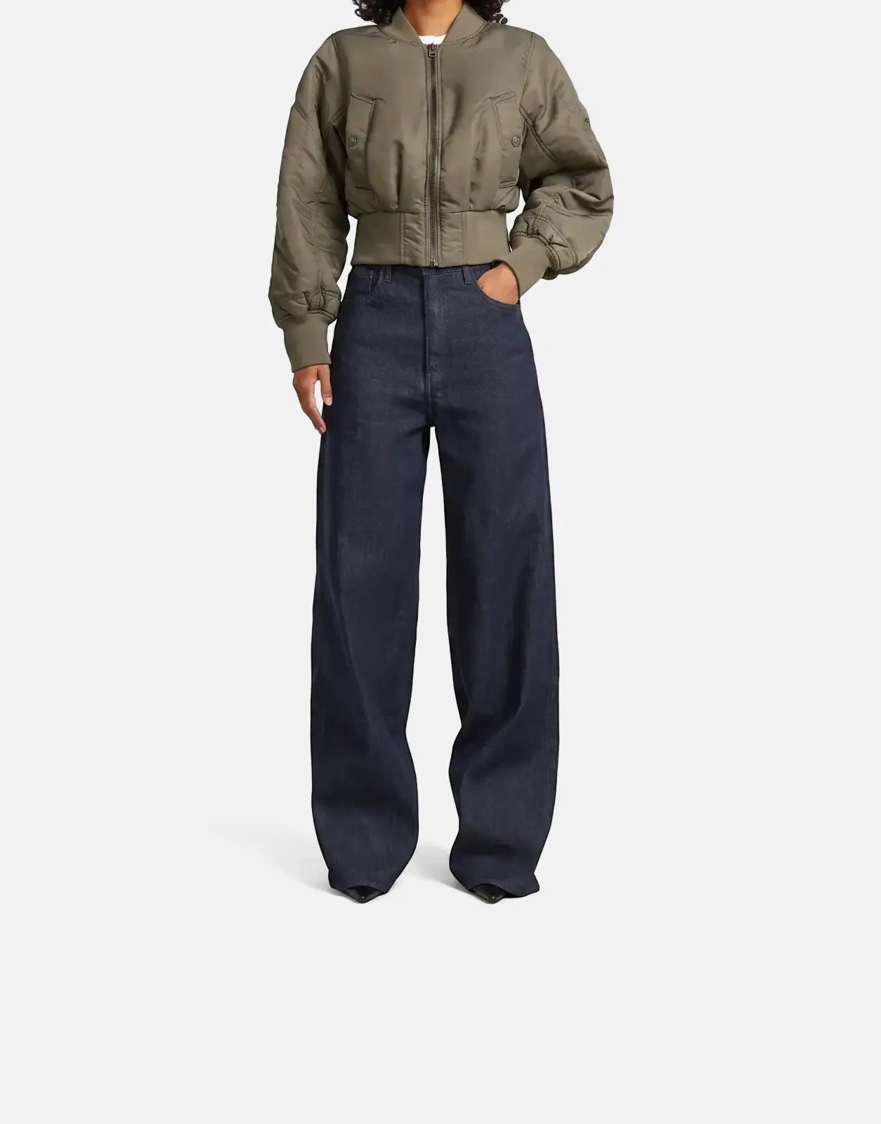 Woman wearing an olive green G-Star RAW Bomber Turf jacket and dark wash jeans, full body front view.