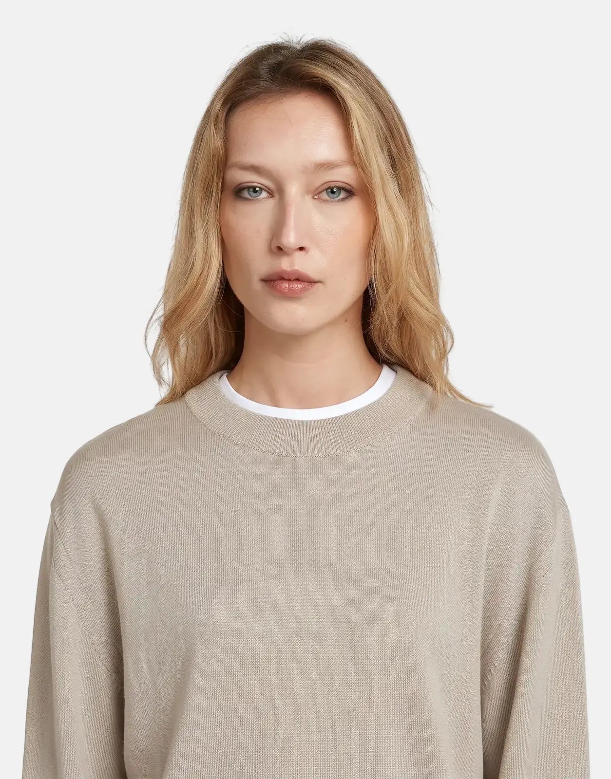 Close-up of a blonde woman wearing a G-Star RAW Boxy Knit Brick sweater in a light beige color, looking directly forward.