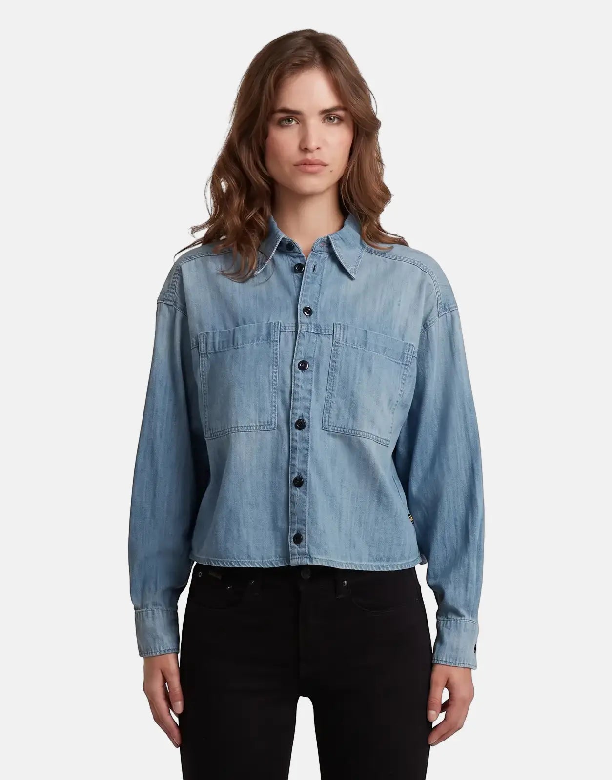 Female model wearing a G-Star RAW Cropped Relaxed Shirt in faded cadet blue denim, featuring long sleeves and button-front