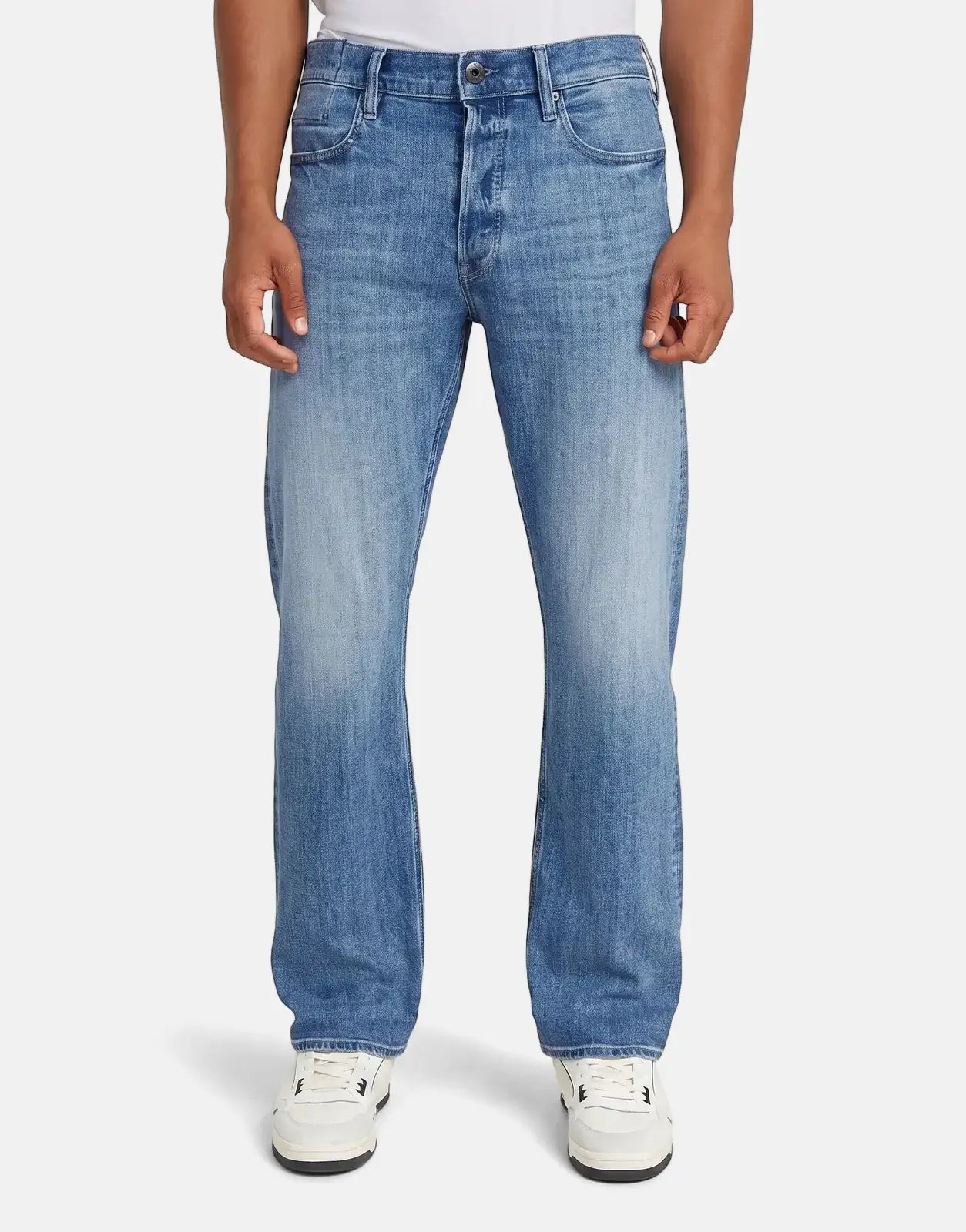 Man wearing G-Star RAW Dakota Regular Faded Niagara Jeans, blue denim with a faded wash, paired with white sneakers.