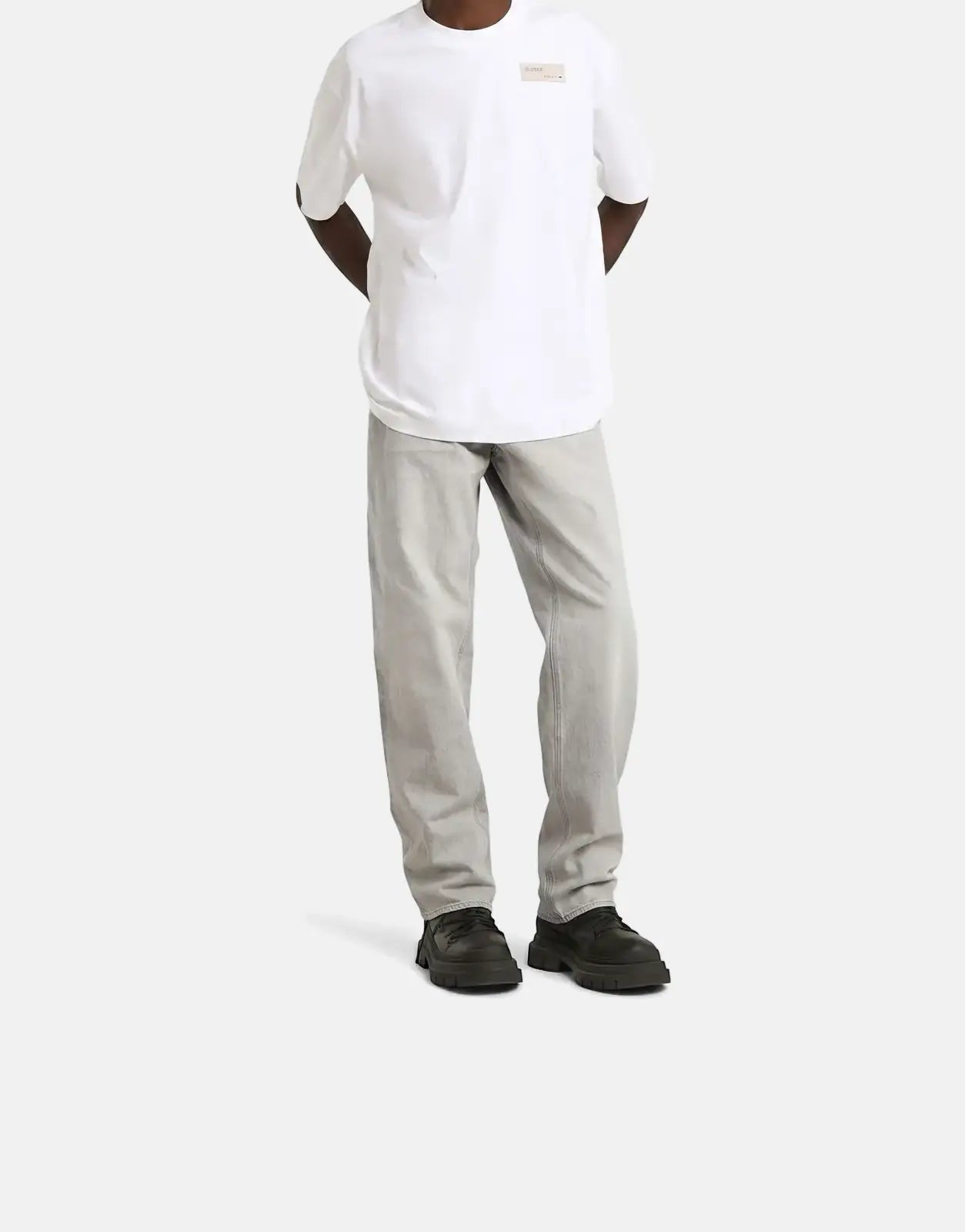 G-Star RAW HB Badge Relaxed White T-Shirt for men, featuring a chest badge, paired with light grey jeans and black shoes.