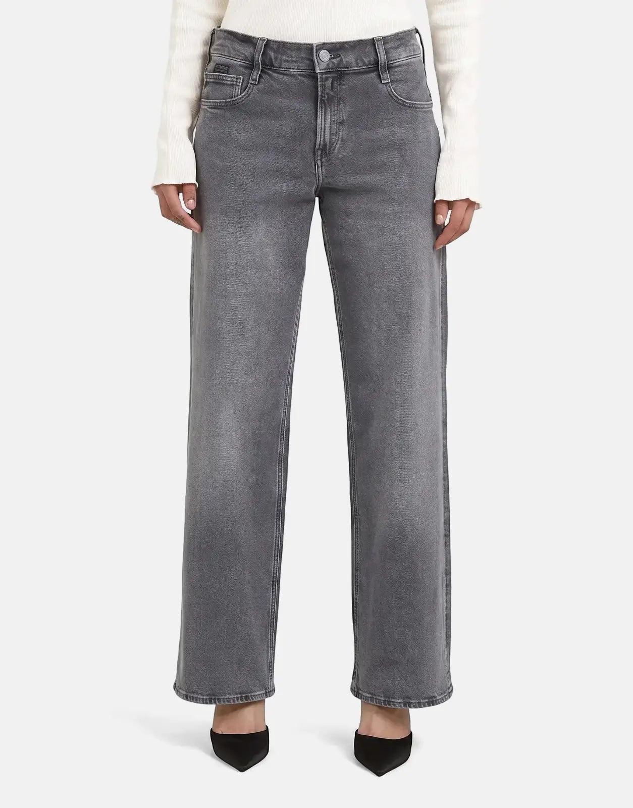 Model wearing G-Star RAW Judee Loose Faded Blade faded gray wide-leg denim jeans with a white sweater and black heels.