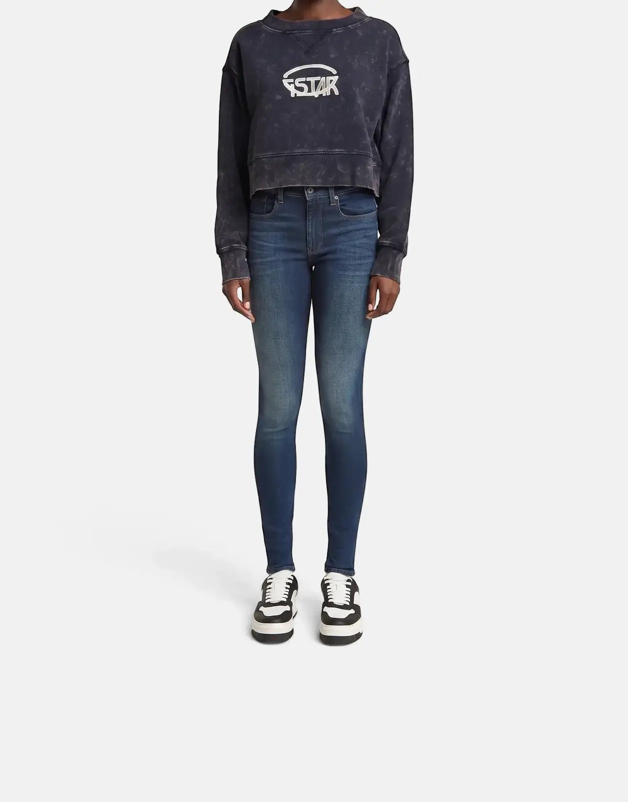 Full body shot of a female model wearing a G-Star RAW Overdyed Cropped Logo Loose Osaka Blue sweatshirt, blue skinny jeans,