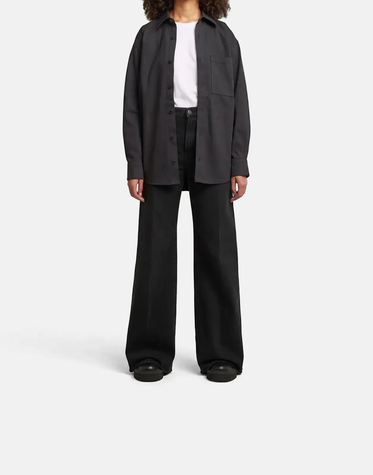 Female model wearing a G-Star RAW Relaxed Overshirt in dark grey raw denim, paired with wide-leg jeans.