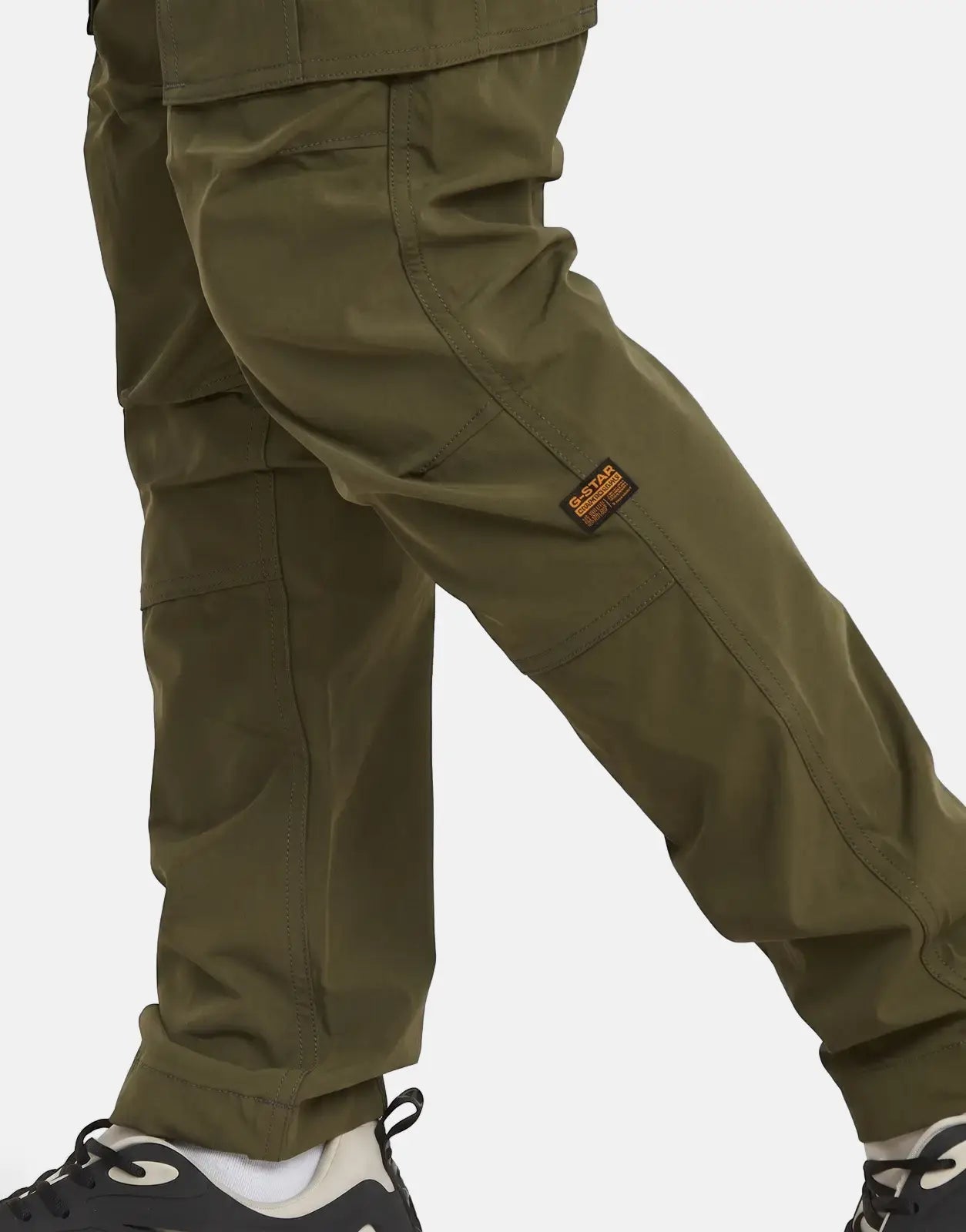 Close-up of G-Star RAW Rovic Zip 3D Regular Tapered cargo pants in shadow olive, paired with black and white sneakers.