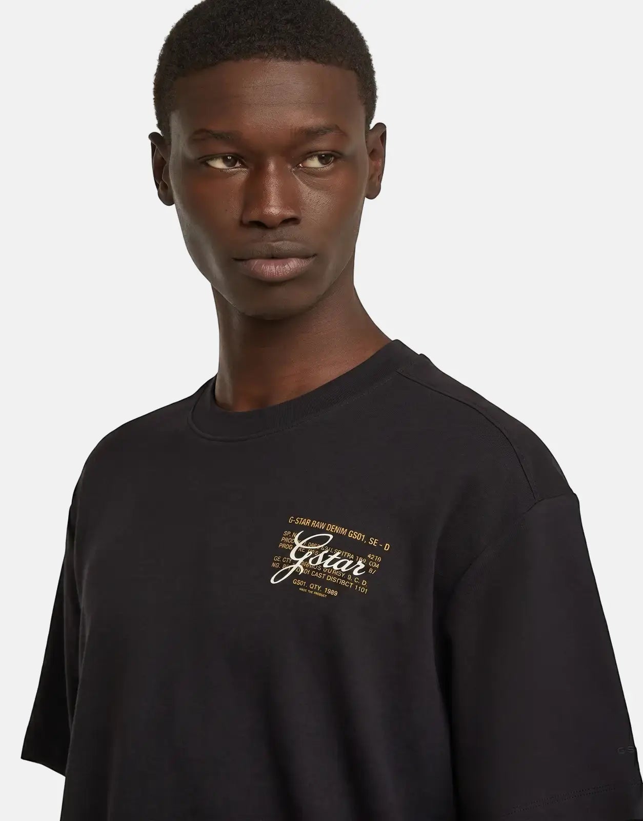 G-Star RAW Script Black T-Shirt, featuring a yellow script logo and text details on the chest, worn by a male model.