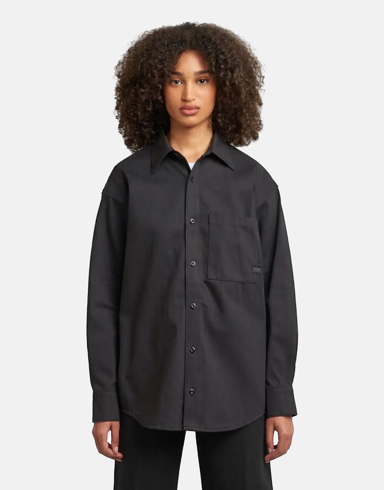 A woman wearing a black G-Star RAW Relaxed Overshirt Raw Denim, featuring a collar, chest pocket, and long sleeves.