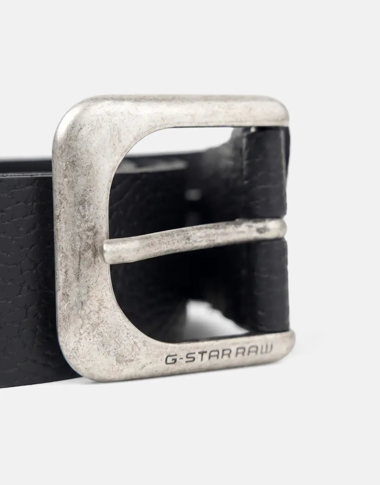 Close-up of a G-Star RAW Zed men's black leather belt with a distressed antic silver buckle featuring engraved branding.