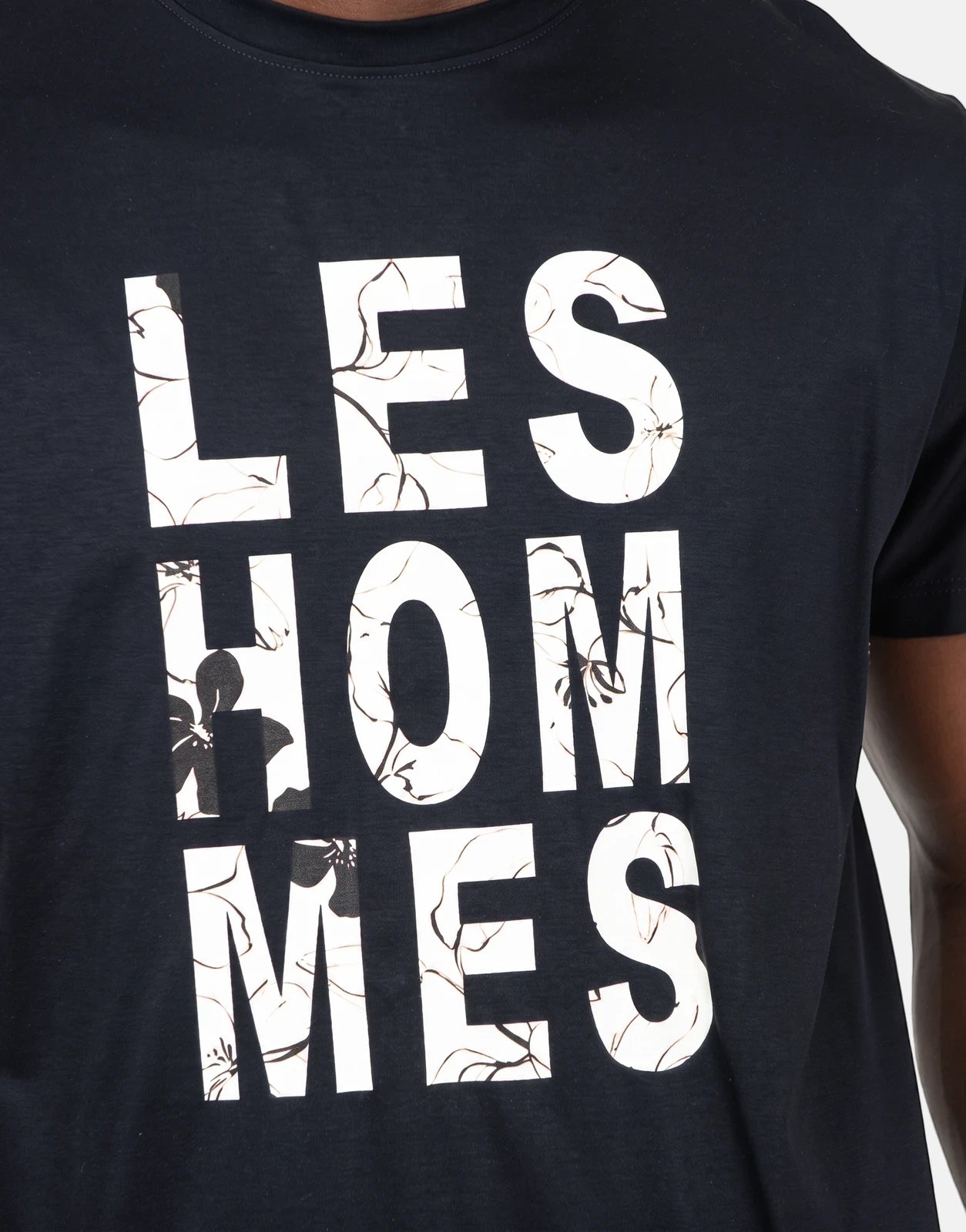 Black Les Hommes short sleeve t-shirt featuring a white chest graphic with floral and branch patterns on a crew neck.