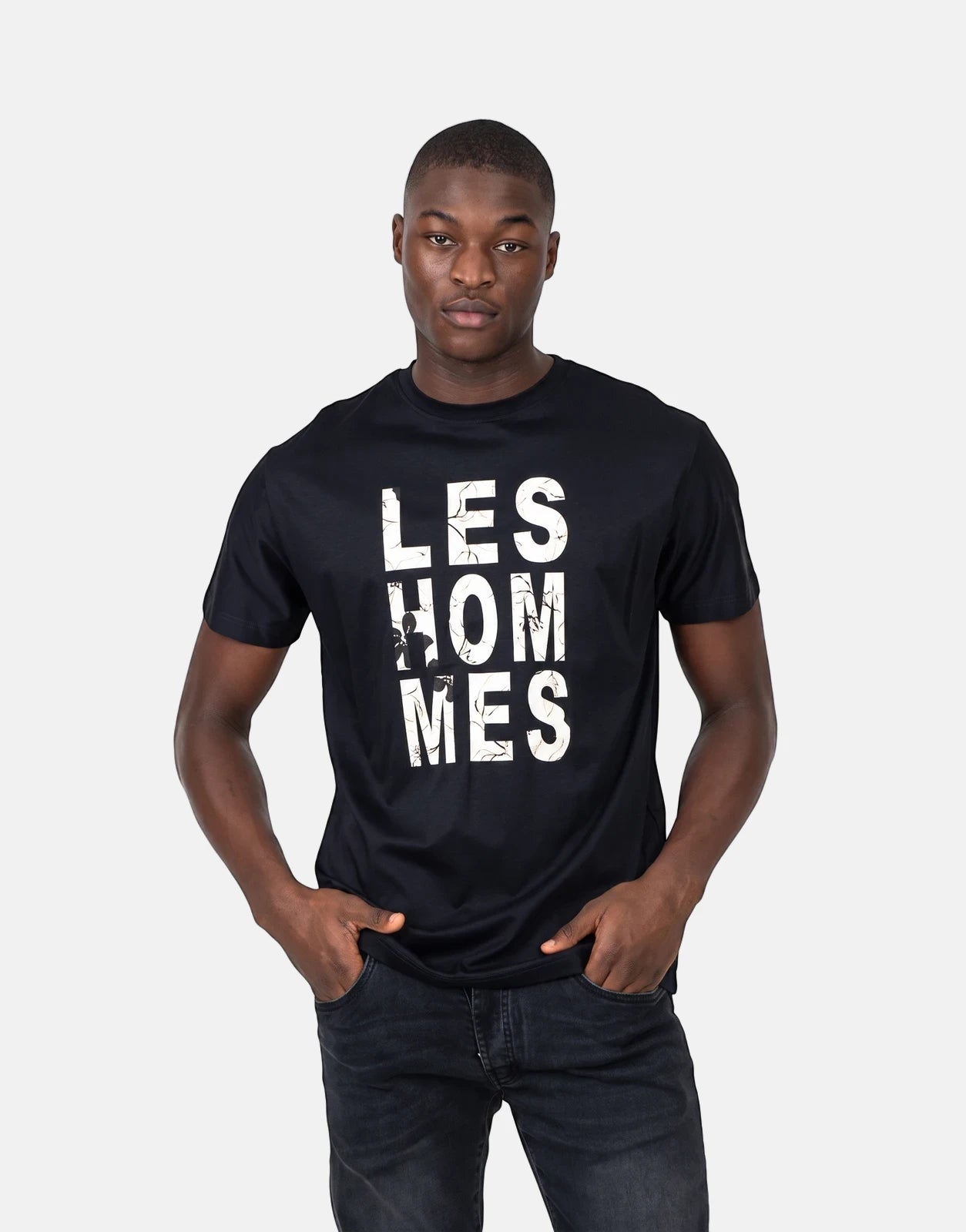Black Les Hommes chest graphic t-shirt worn by a male model with hands in pockets, front view.
