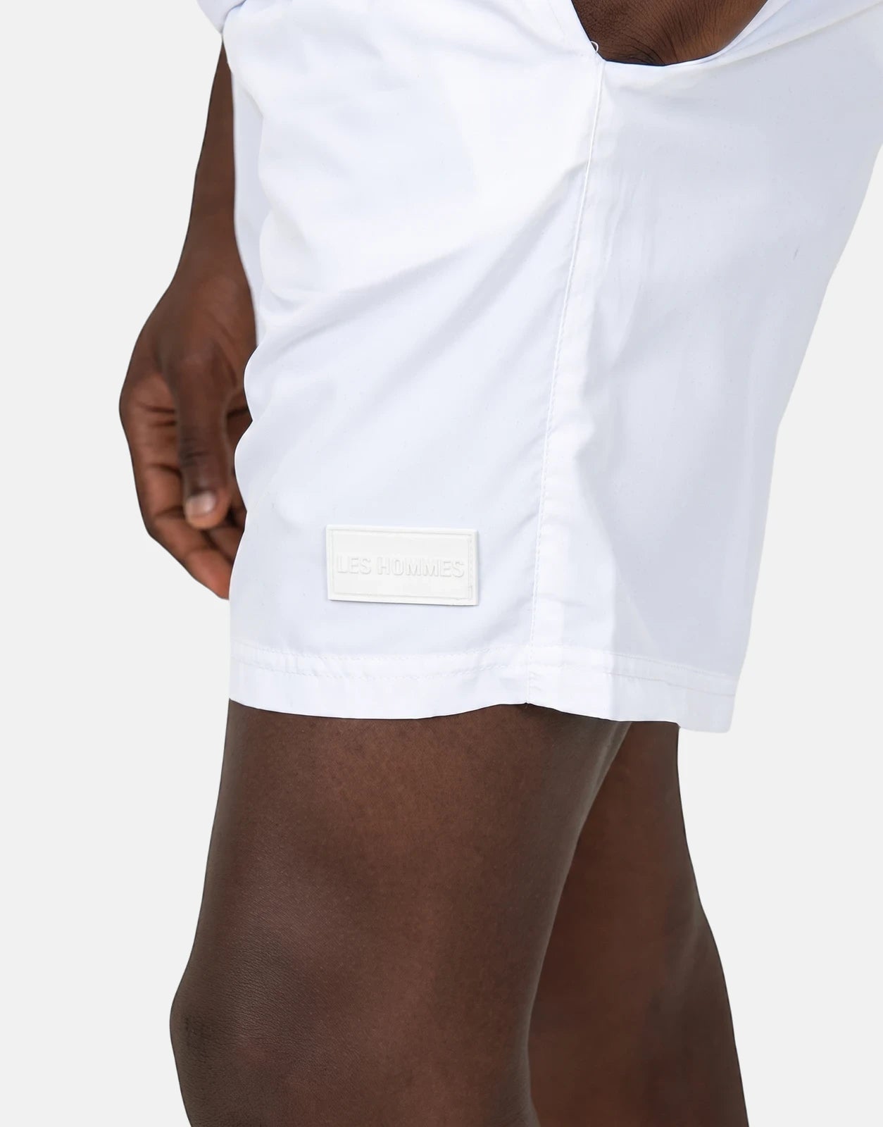 Les Hommes Colour White Swim Shorts in white fabric with clean stitching and a subtle logo patch on the hem for a sleek,
