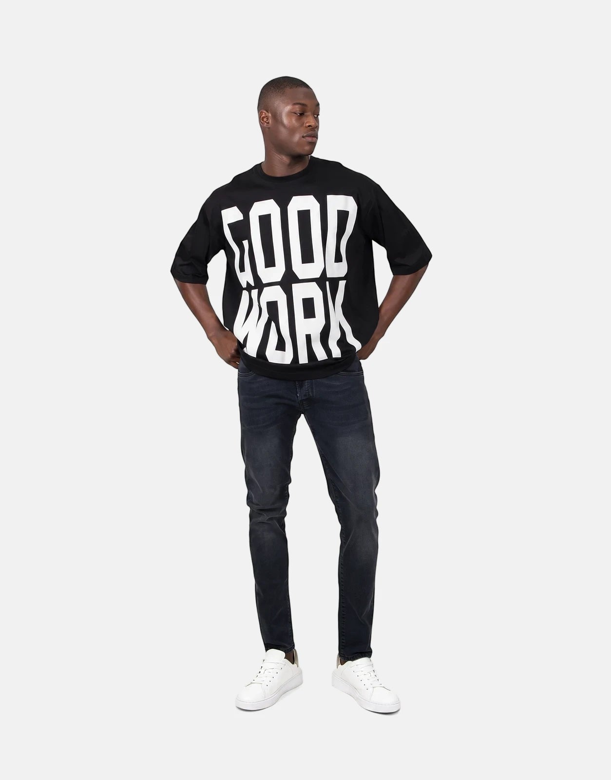 Les Hommes Good Work Black T-Shirt on a male model wearing dark wash jeans and white sneakers.