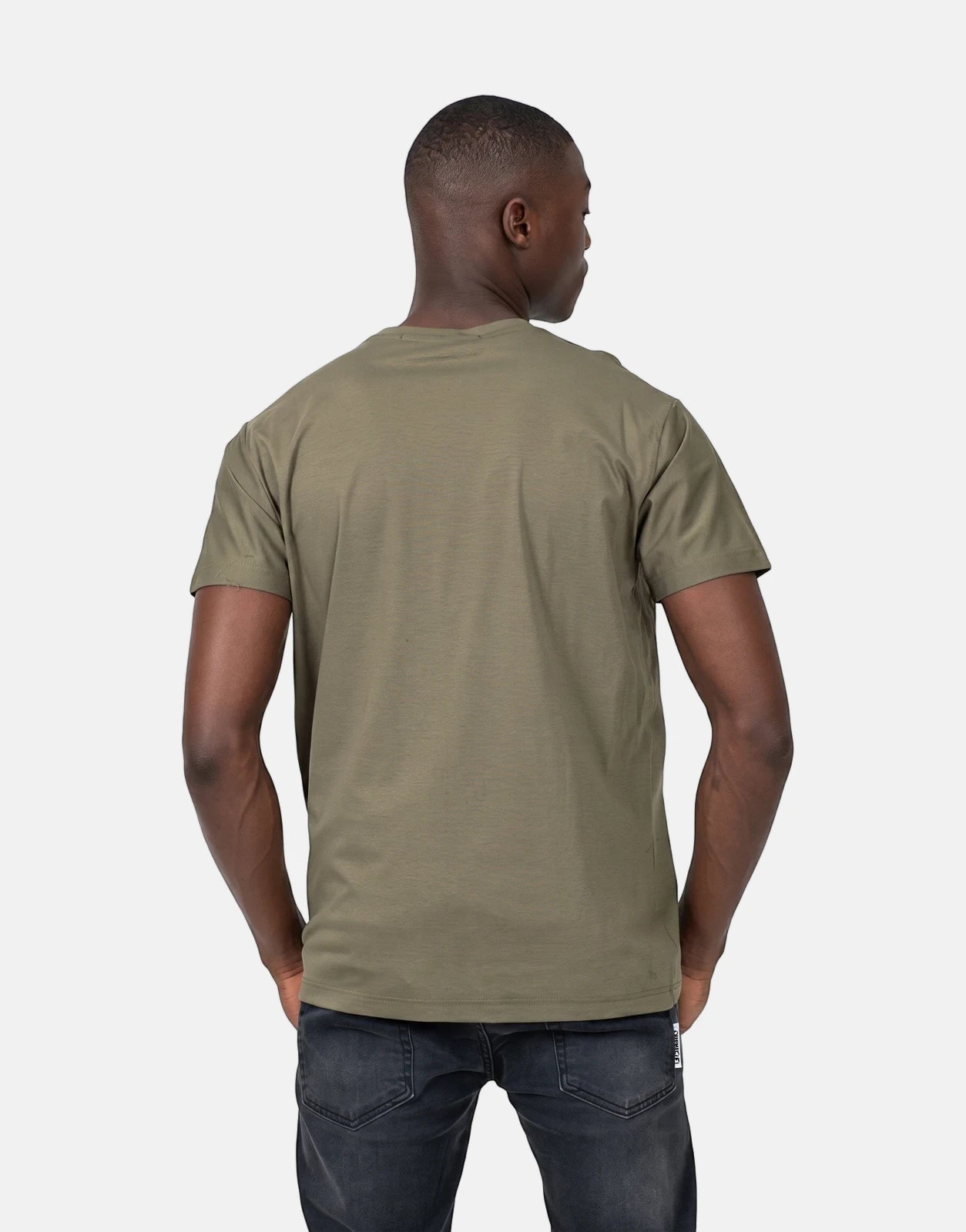 Back view of a male model wearing an olive green Les Hommes t-shirt and dark jeans.