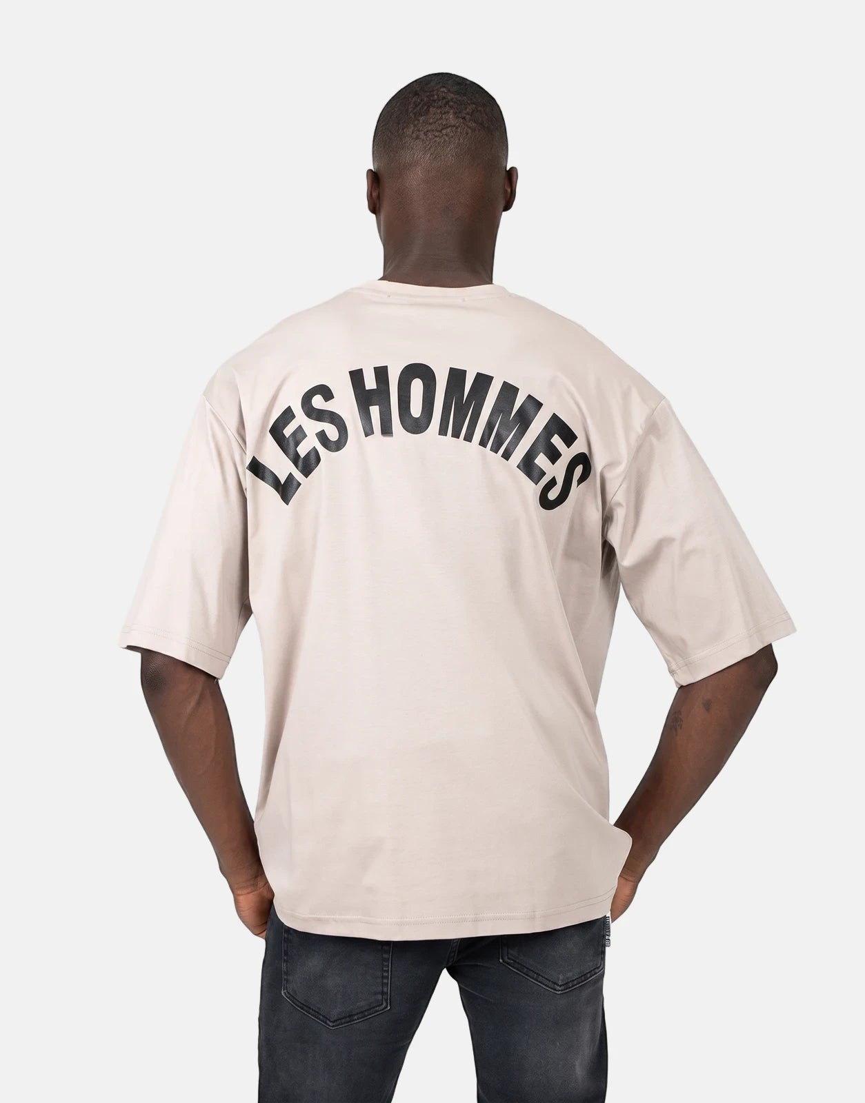 Men's Les Hommes oversized brown t-shirt featuring a distinctive black 'LES HOMMES' logo arched across the back.