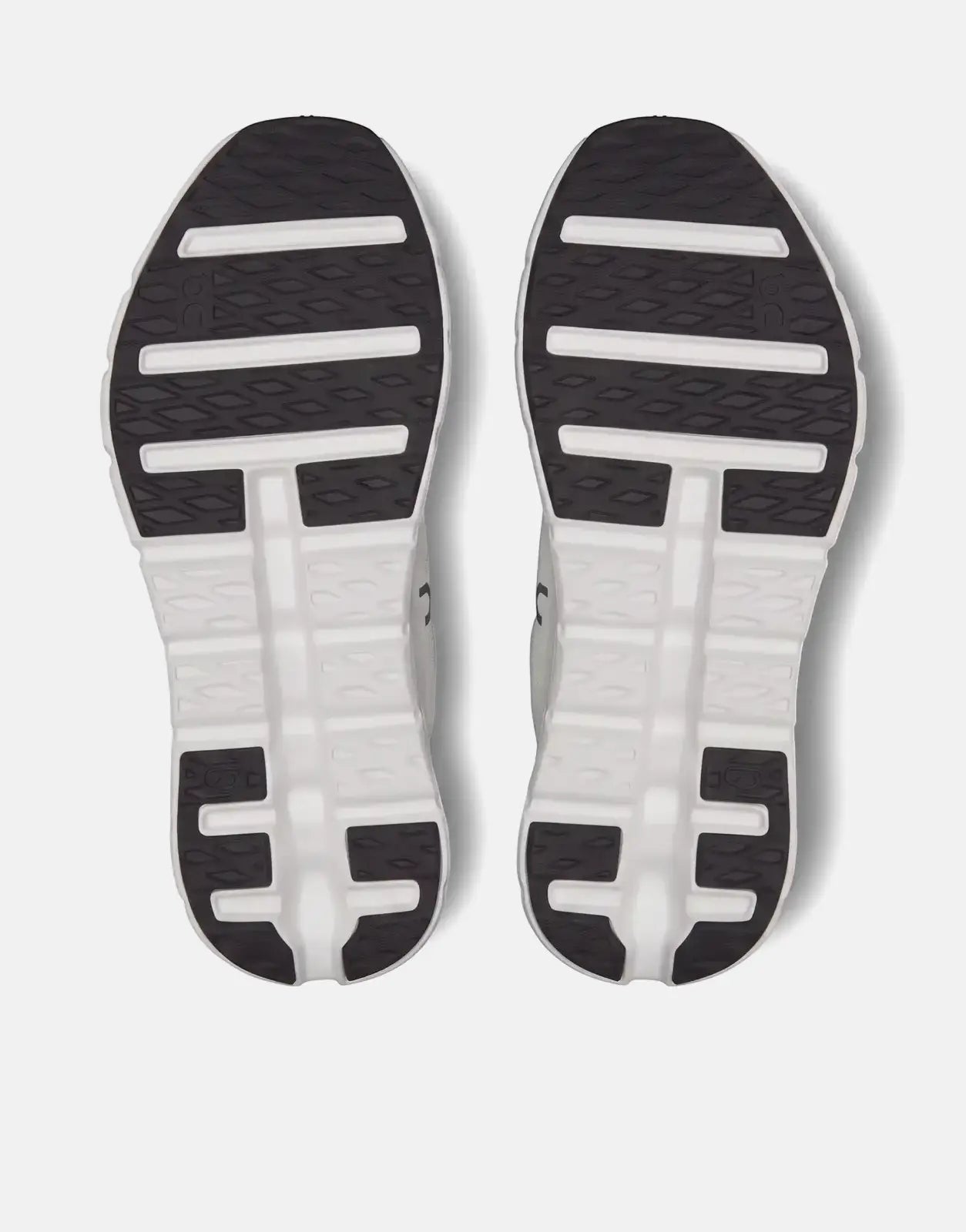 Bottom view of two On Unisex Cloudtilt Black Ivory running sneakers, showcasing the black and white textured soles.