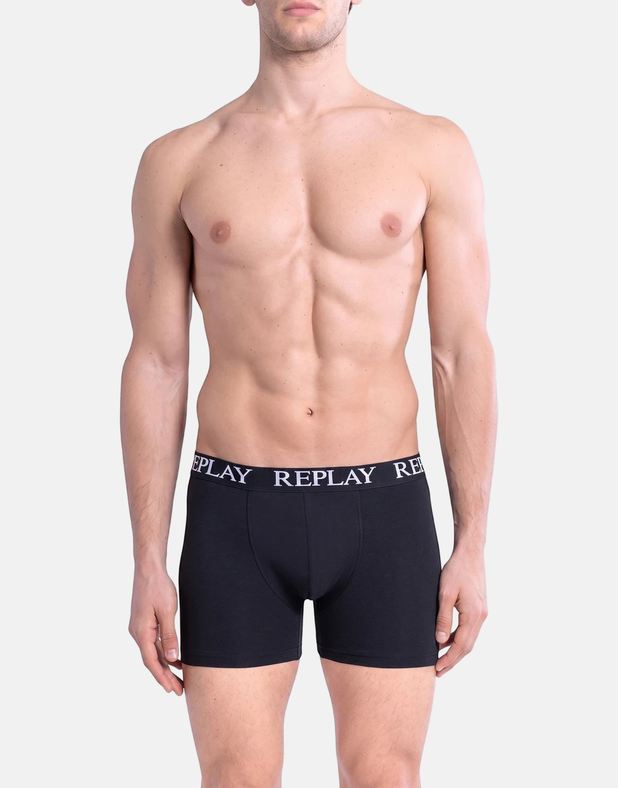 Replay men's black boxer briefs worn by a model, featuring a white branded waistband and a mid-thigh length.