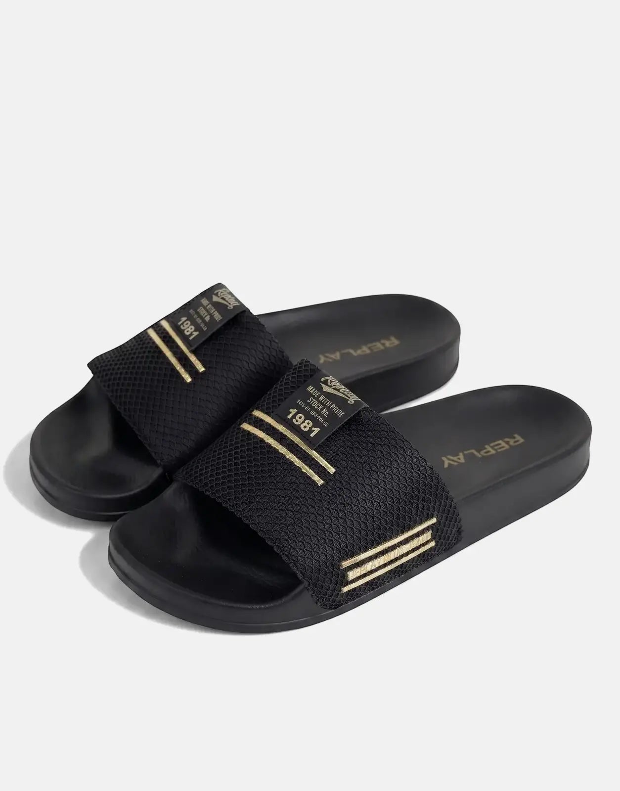 Black Replay Up Trap slides with textured straps and gold branding arranged side-by-side on a light surface.
