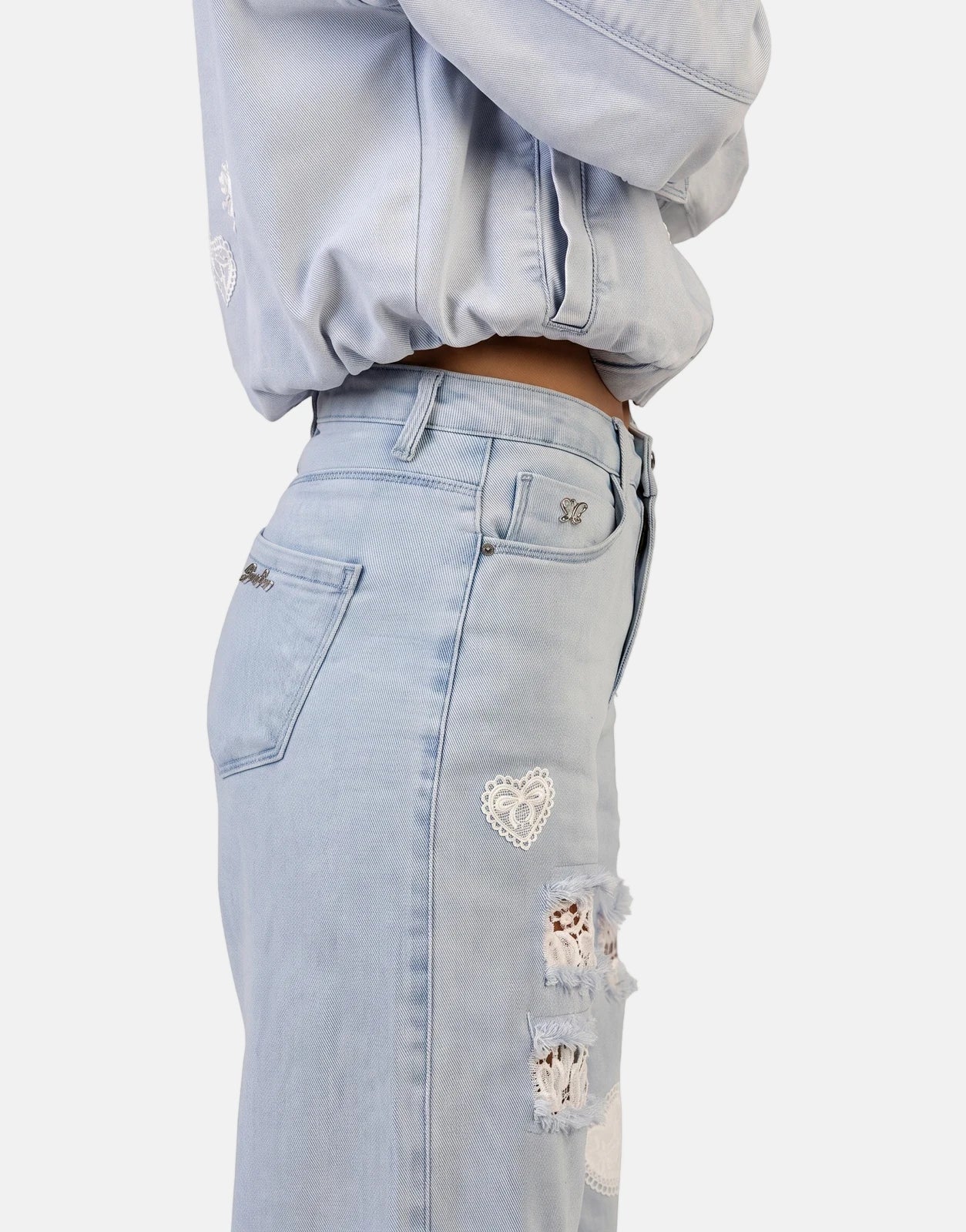Close-up of Sissy Boy Kiera wide leg light vintage jeans featuring distressed details with white lace and heart-shaped