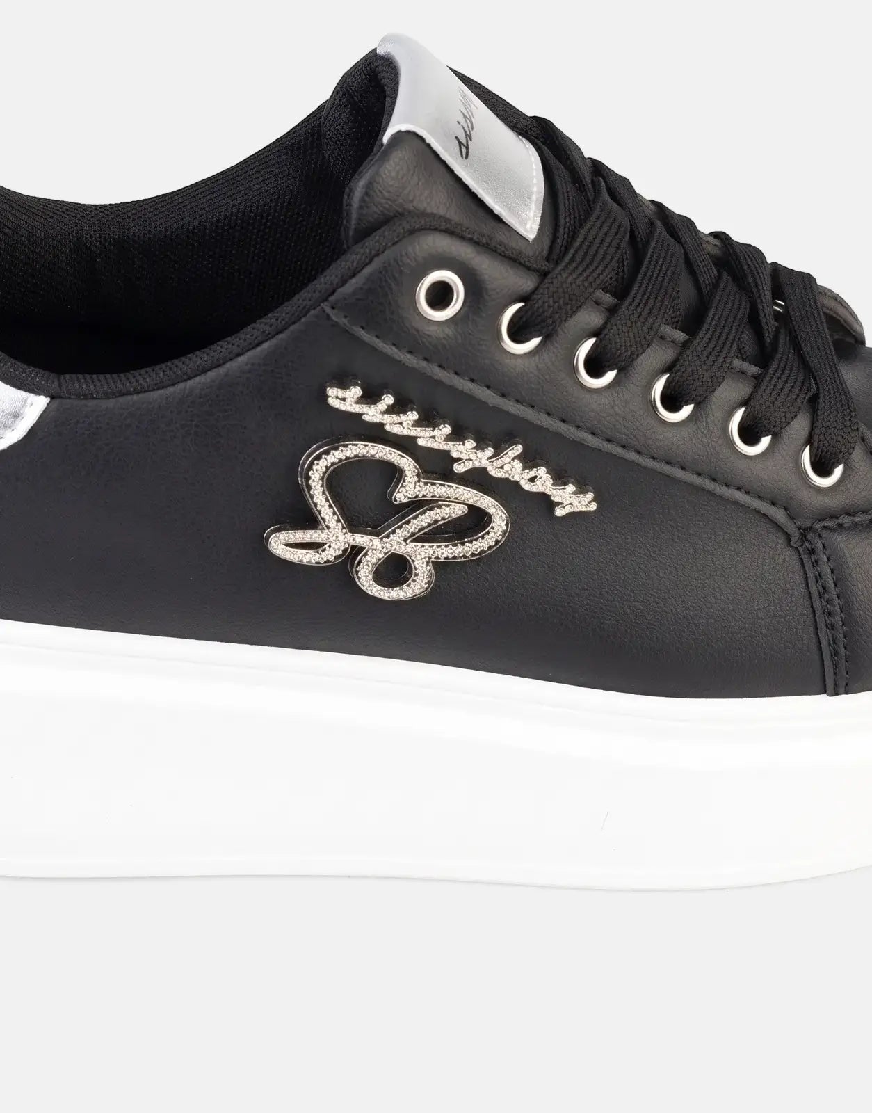 Close-up of Sissy Boy Noella black sneakers with silver accents, white platform sole, and a sparkling logo on the side,