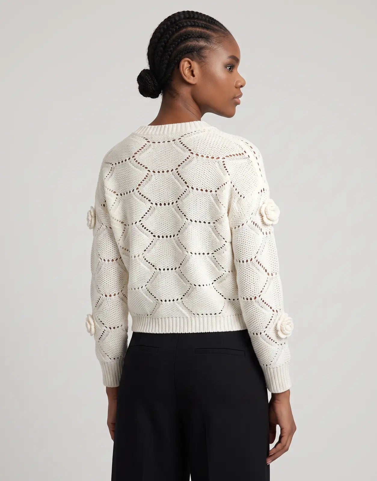 Back view of a model wearing a Sissy Boy Wallflower Knit Off White Jersey sweater, featuring an open knit diamond pattern