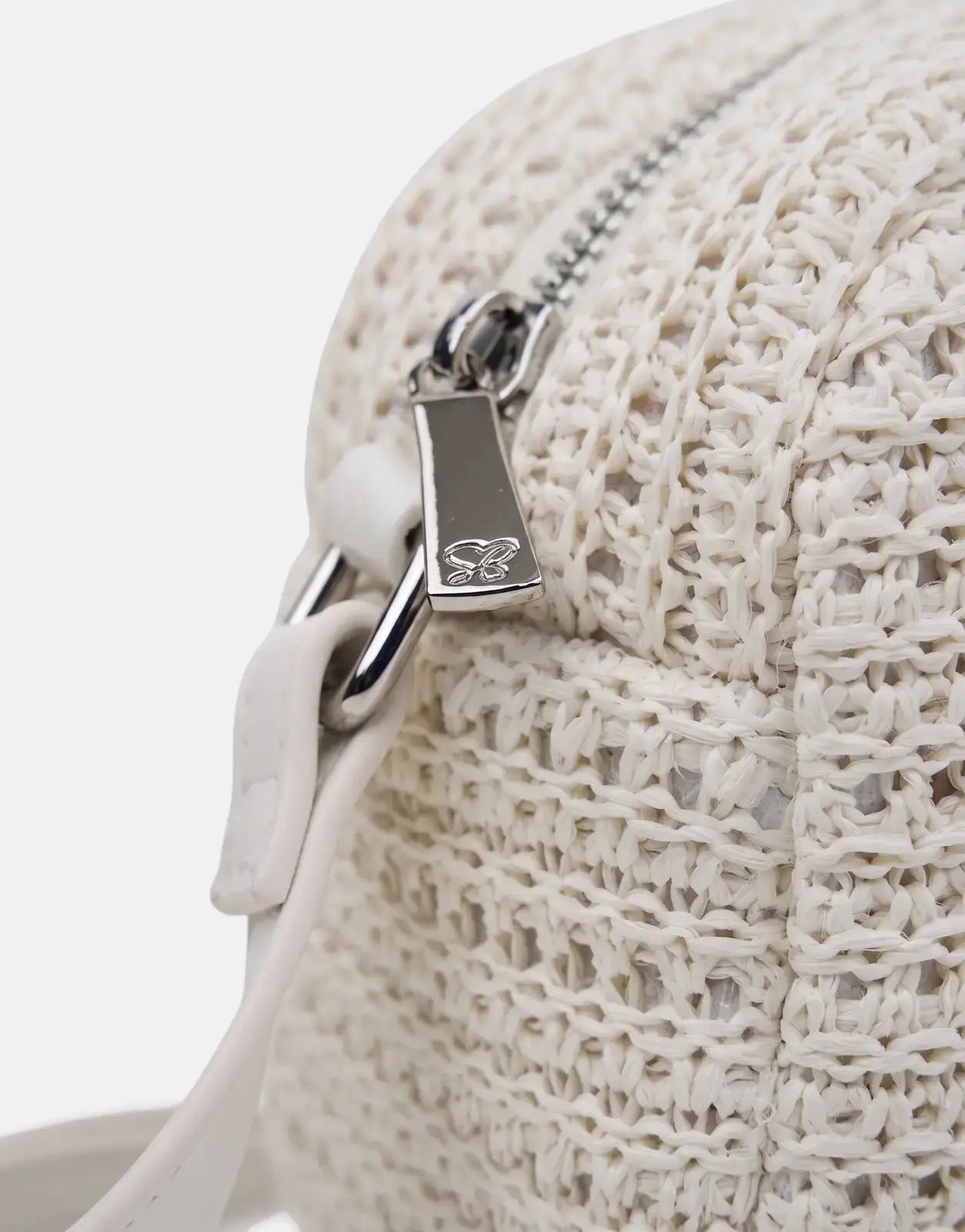 Close-up view of an off-white knitted Sissy Boy Wren bag featuring a silver zipper with a logo and a white strap.