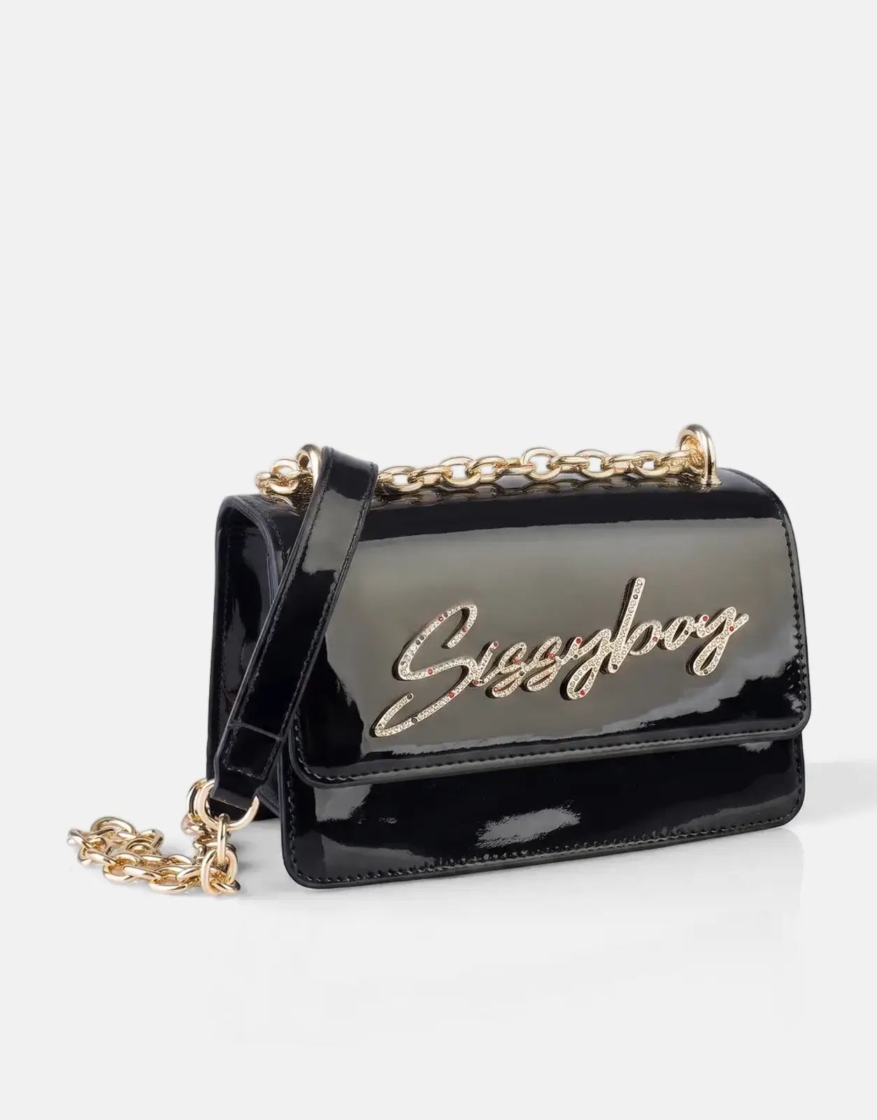 Black patent leather Sissyboy crossbody bag with gold chain strap and rhinestone logo, presented at an angle on a reflective