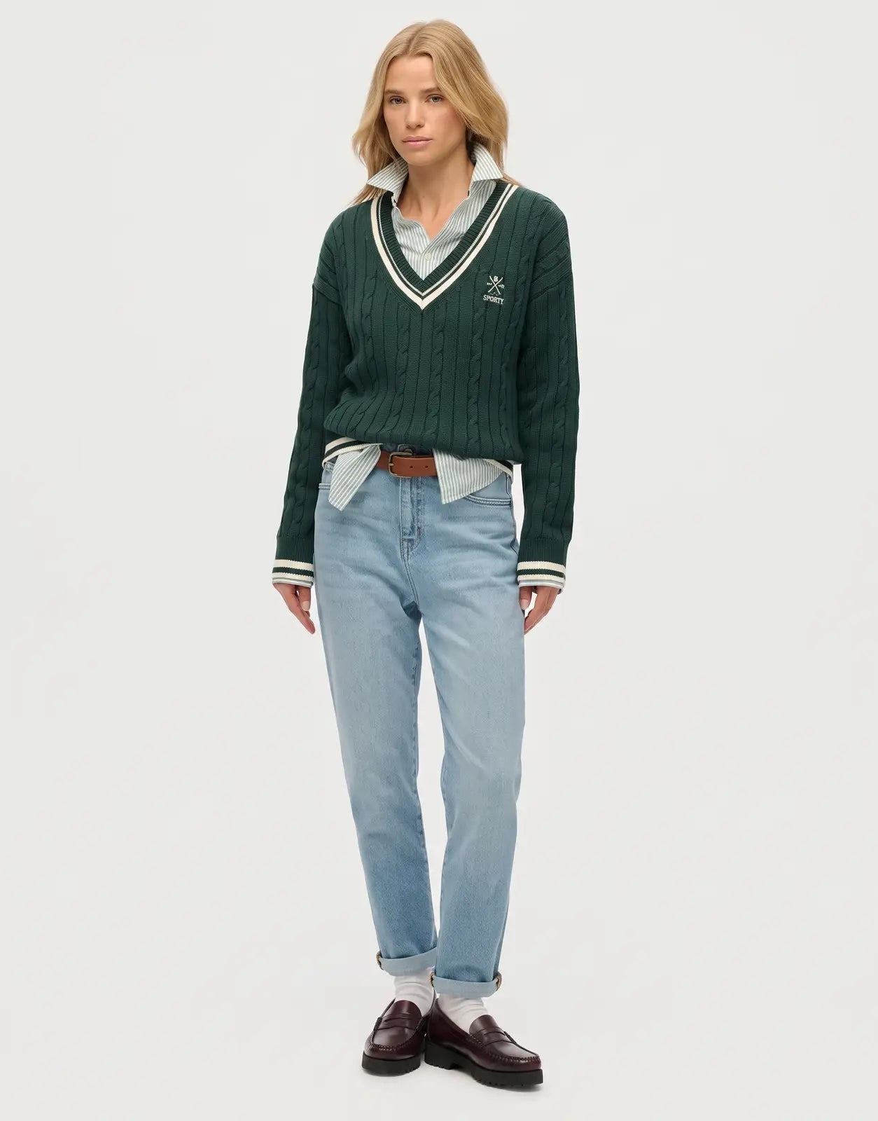 Front view of a Superdry Cricket Club enamel green cable knit V-neck jumper, worn by a female model in a studio setting.