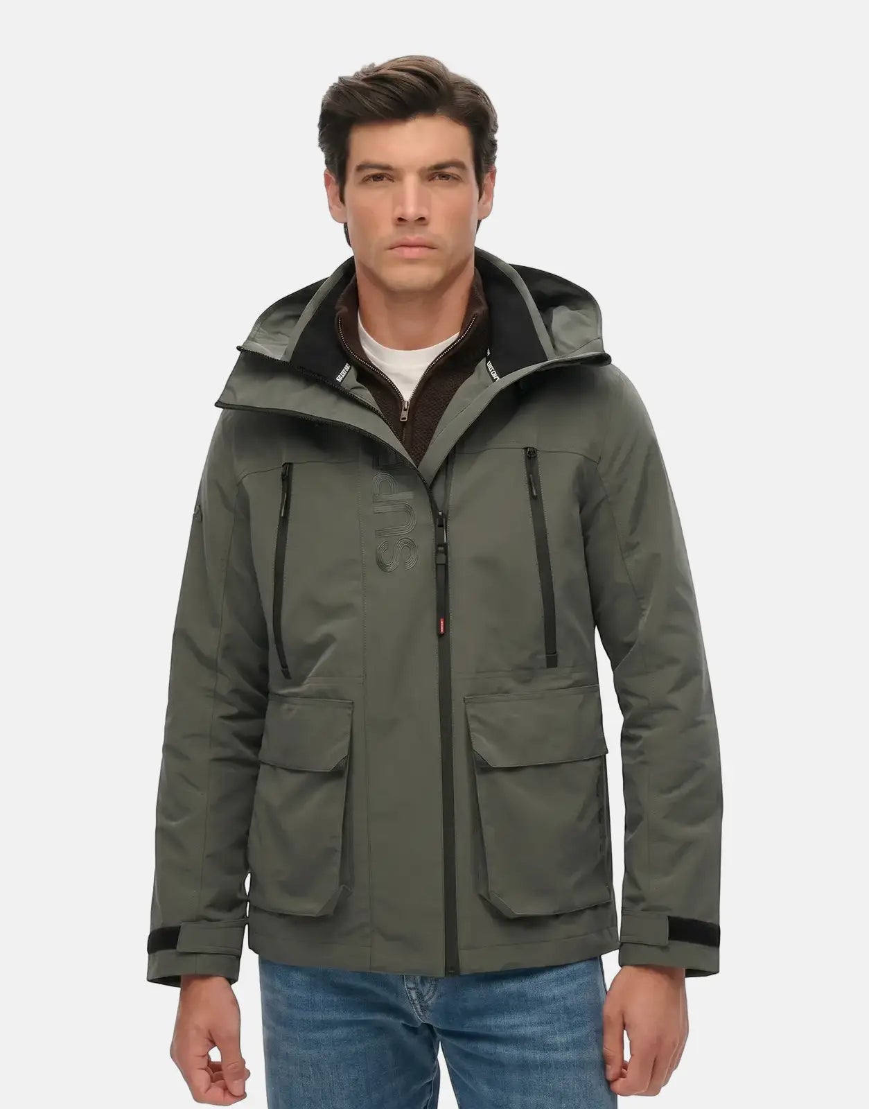 A male model wears a dark dull charcoal Superdry Hood Ultimate Windbreaker jacket with multiple zipper pockets and a hood.