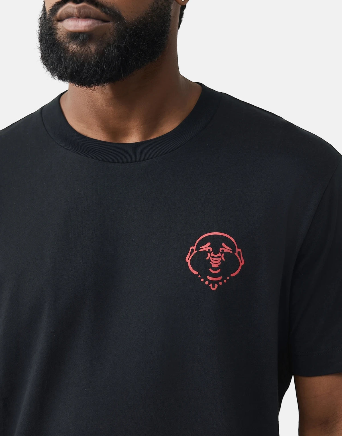 Close-up of a man wearing a black True Religion Abstract Denim T-Shirt featuring a red Buddha logo on the chest.